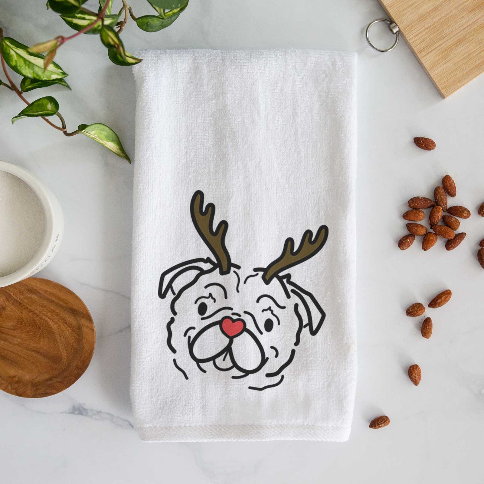 Minimalist line drawing of Pip the Pug with reindeer antlers and a red nose on a decorative hand towel