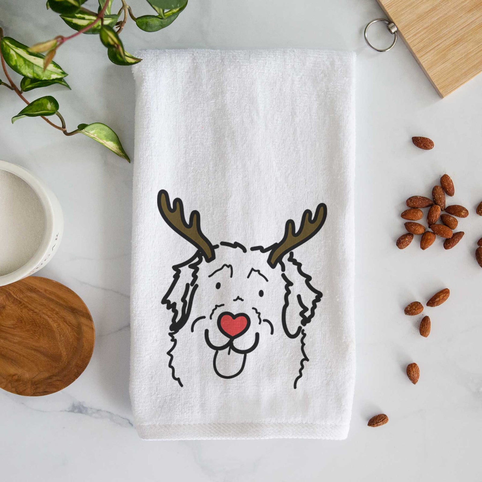 Minimalist line drawing of Sabre the Leonberger with reindeer antlers and a red nose on a decorative hand towel