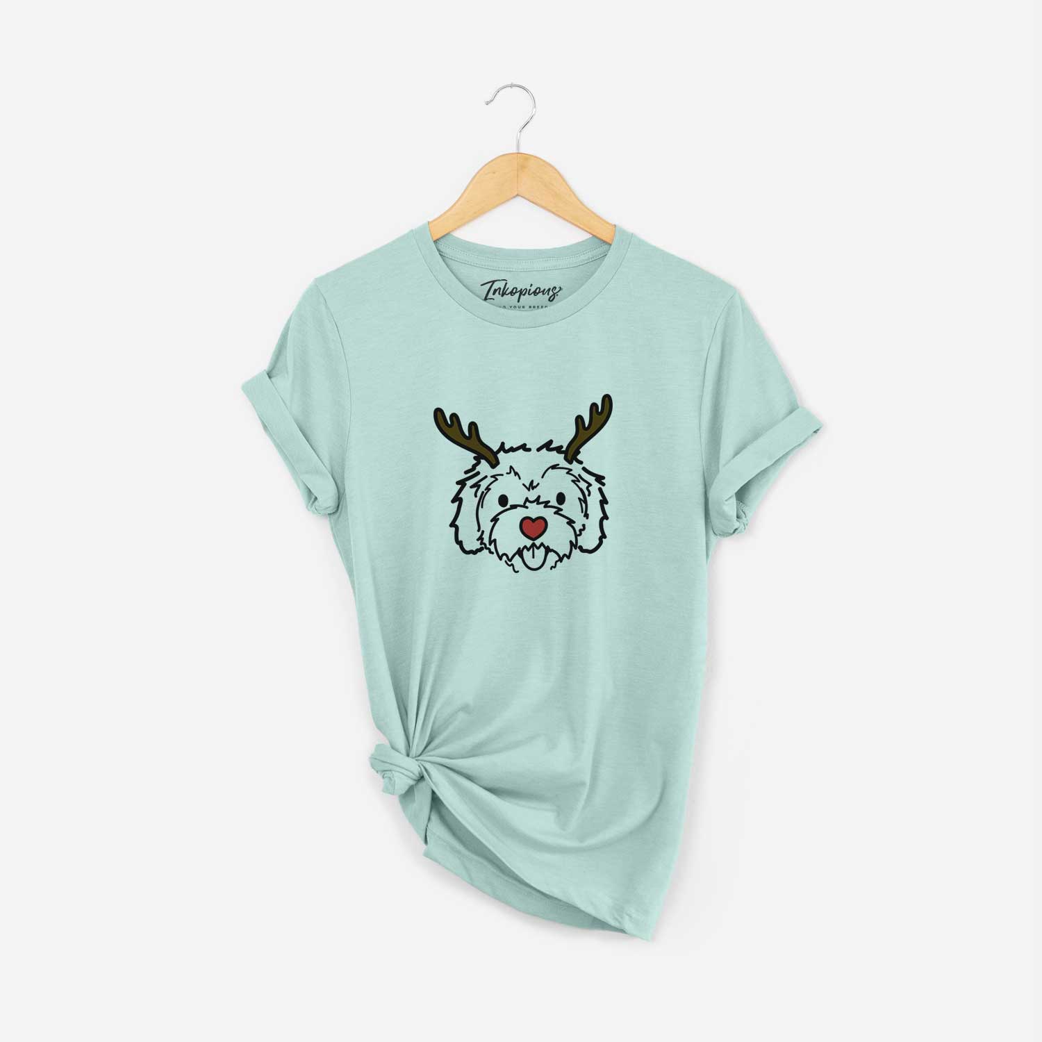 Minimalist line drawing of Sprinkles the Cockapoo with reindeer antlers and a red nose on a Heather Sage Unisex crewneck