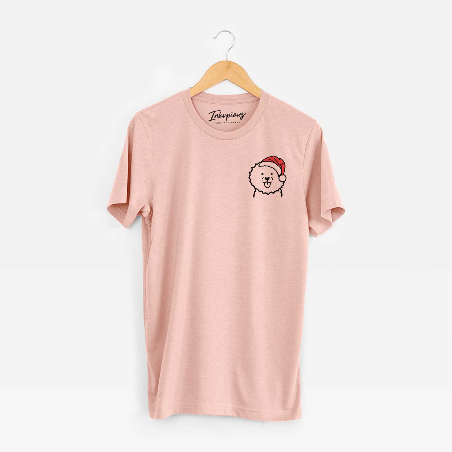 Small chest-pocket minimalist line drawing of a Bichon Frise wearing a Santa hat on a Peach Unisex crewneck