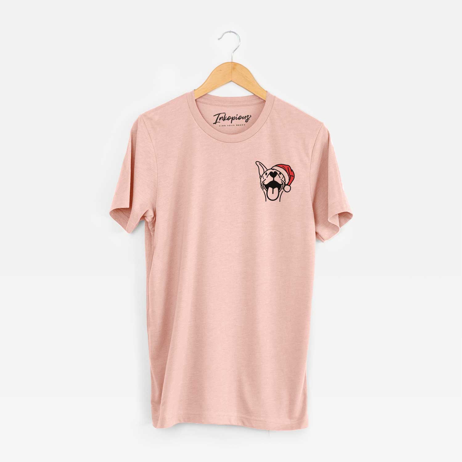 Small chest-pocket minimalist line drawing of Merlin the Basenji wearing a Santa hat on a Peach Unisex crewneck