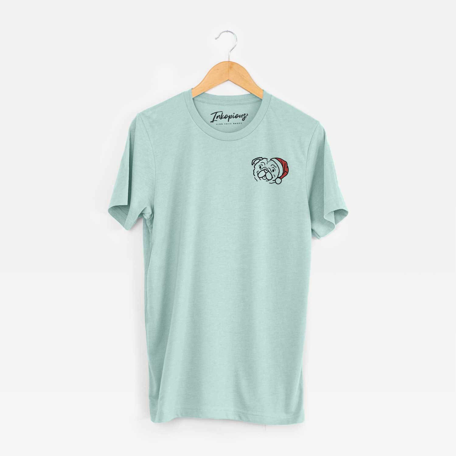 Small chest-pocket minimalist line drawing of Pip the Pug wearing a Santa hat on a Heather Sage Unisex crewneck
