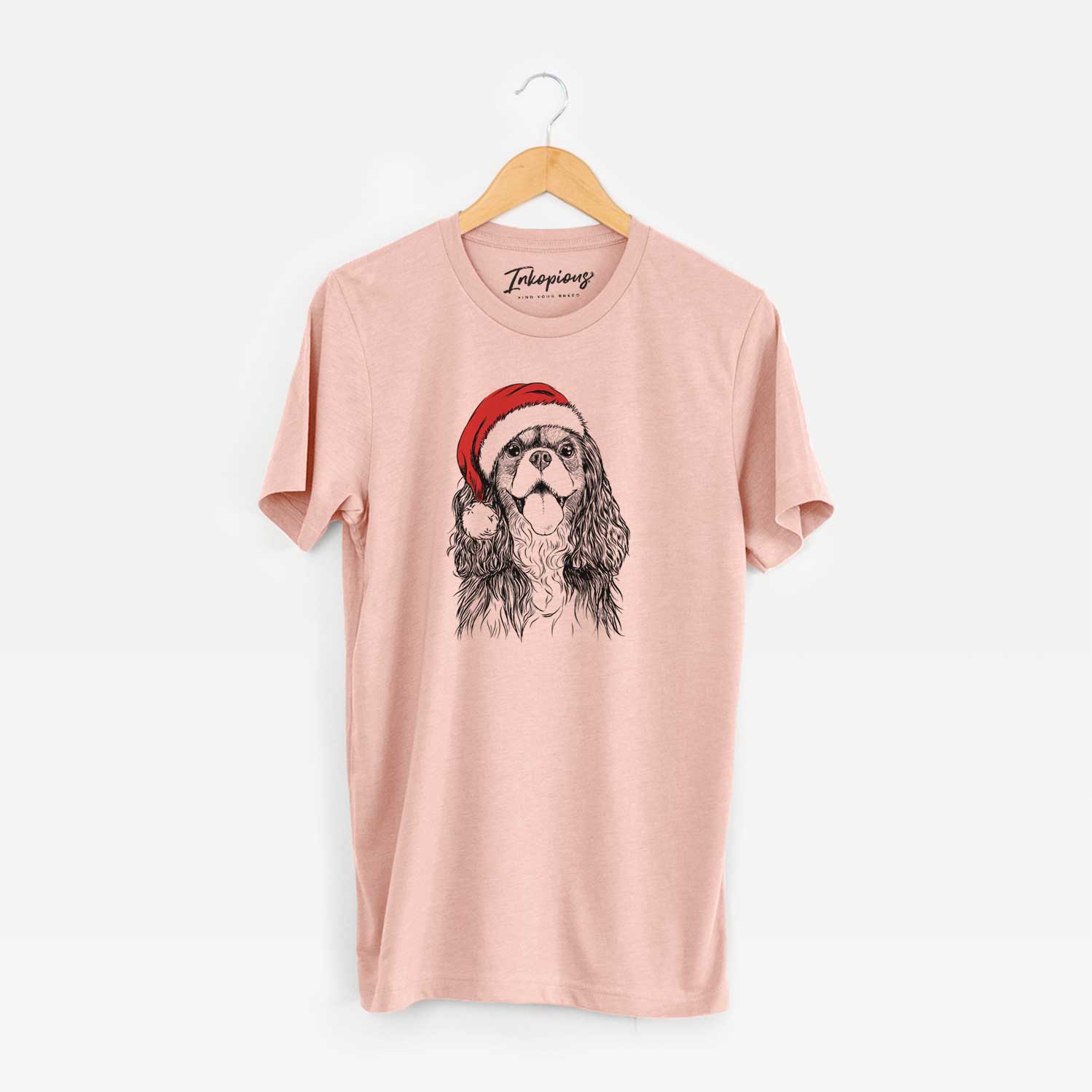 Hand-drawn sketch of Brandy the Cavalier King Charles Spaniel wearing a Santa hat on a Peach Unisex crewneck
