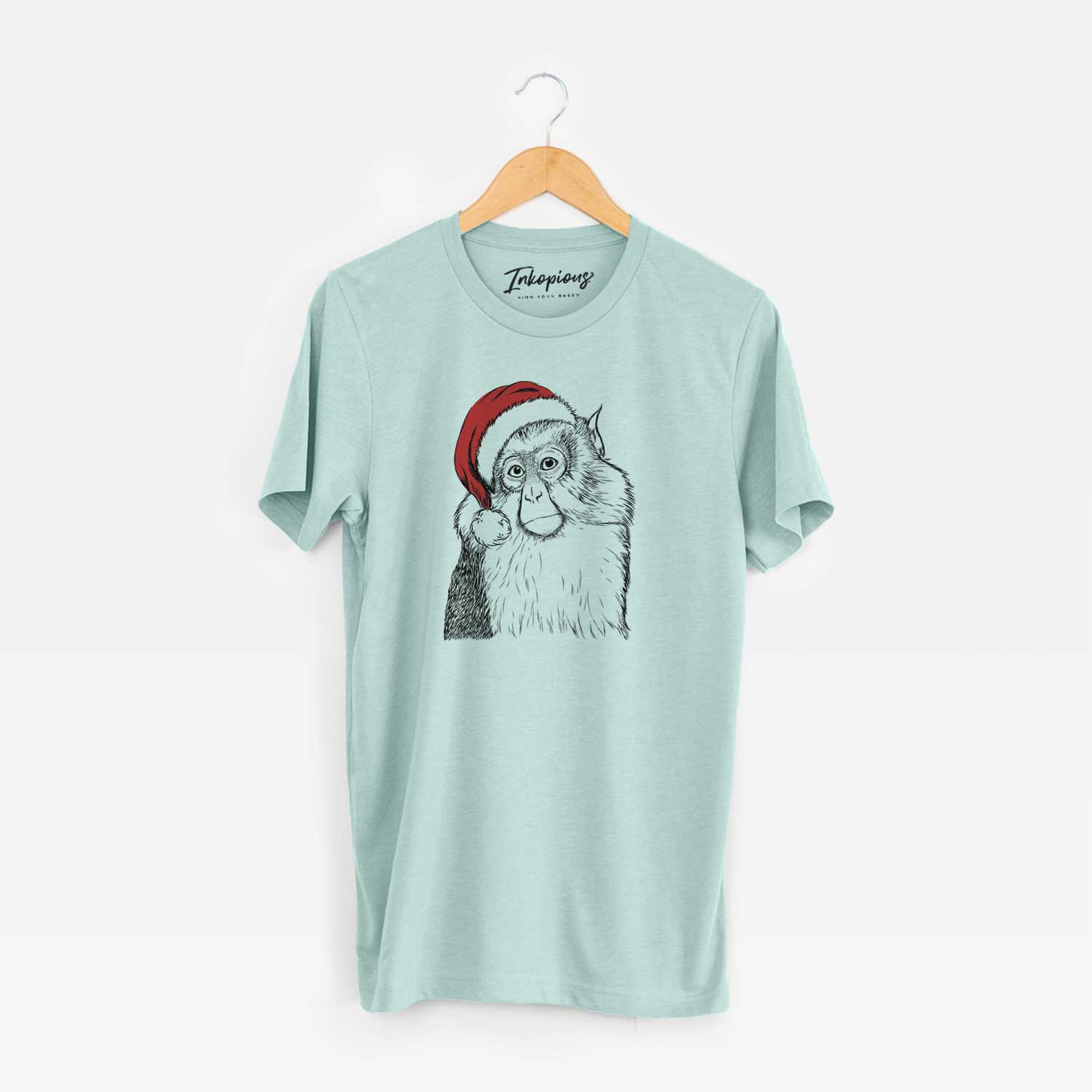 Hand-drawn sketch of Matata the Mona Monkey wearing a Santa hat on a Heather Sage Unisex crewneck
