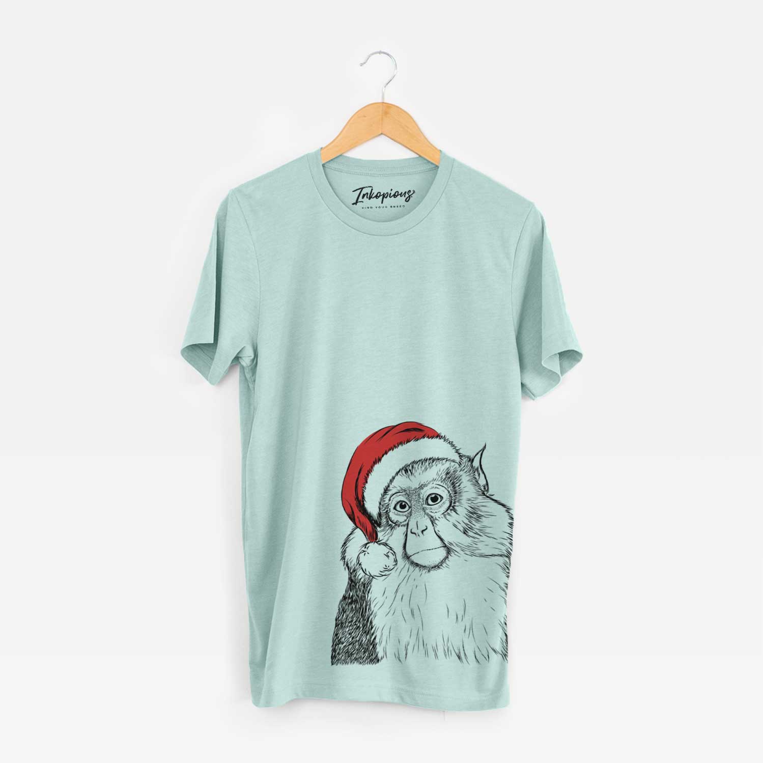 Hand-drawn sketch of Matata the Mona Monkey wearing a Santa hat on a Heather Sage Unisex crewneck