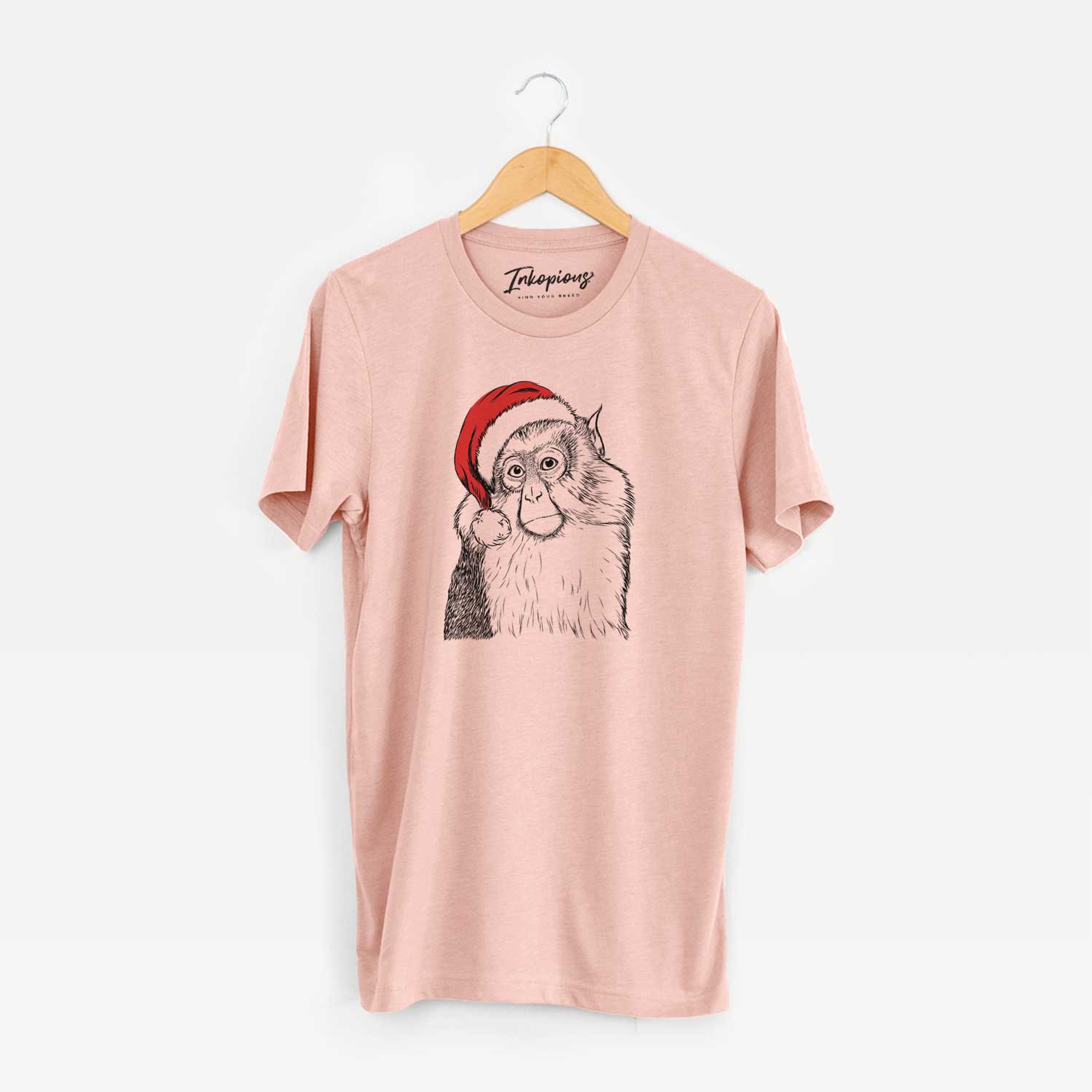 Hand-drawn sketch of Matata the Mona Monkey wearing a Santa hat on a Peach Unisex crewneck