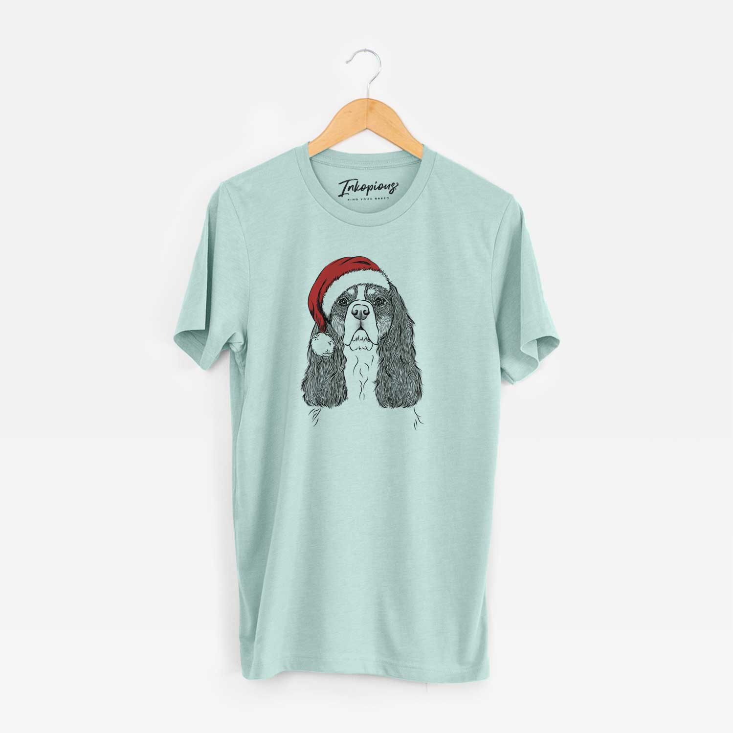 Hand-drawn sketch of Sebastian the Cavalier King Charles Spaniel wearing a Santa hat on a Heather Sage Unisex crewneck