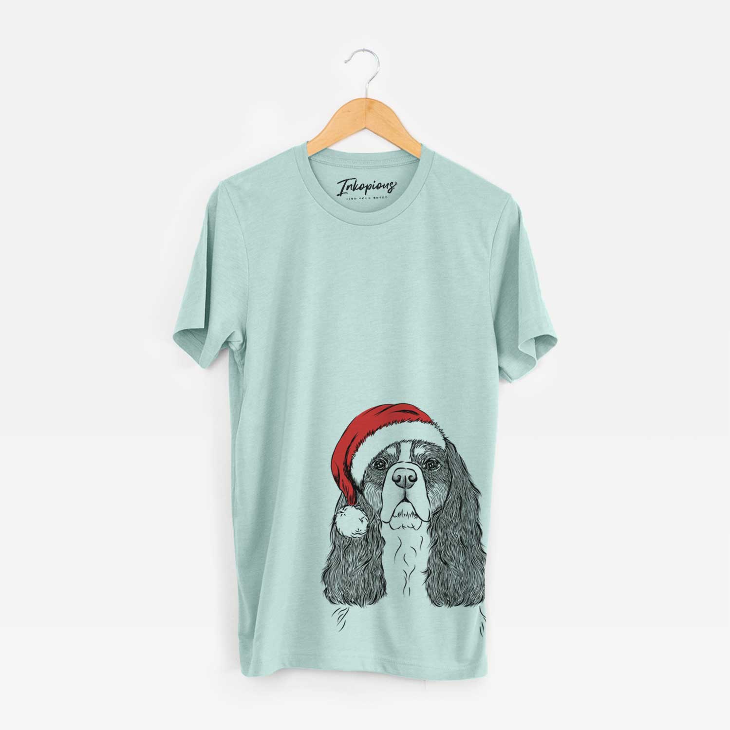 Hand-drawn sketch of Sebastian the Cavalier King Charles Spaniel wearing a Santa hat on a Heather Sage Unisex crewneck