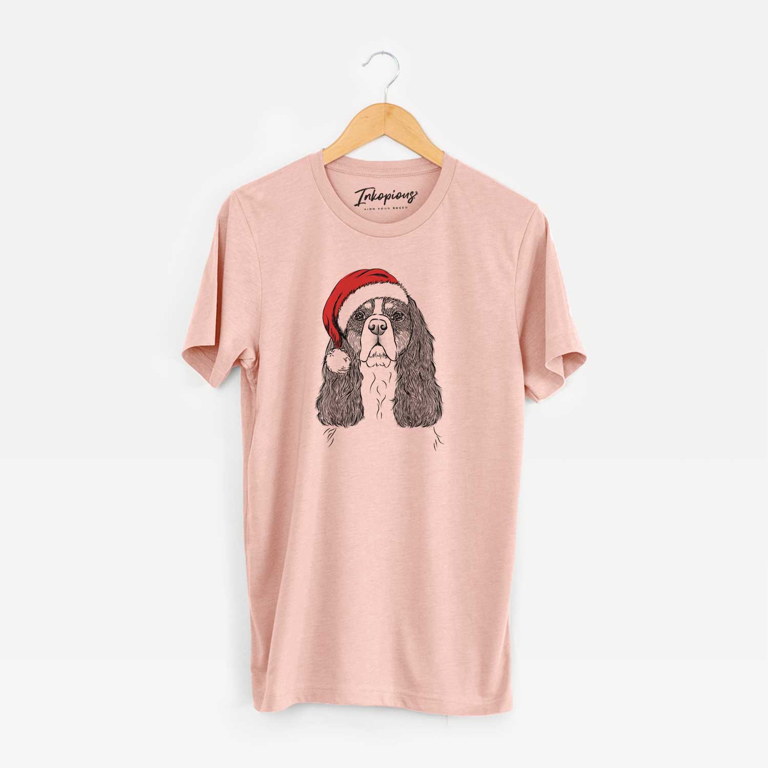 Hand-drawn sketch of Sebastian the Cavalier King Charles Spaniel wearing a Santa hat on a Peach Unisex crewneck