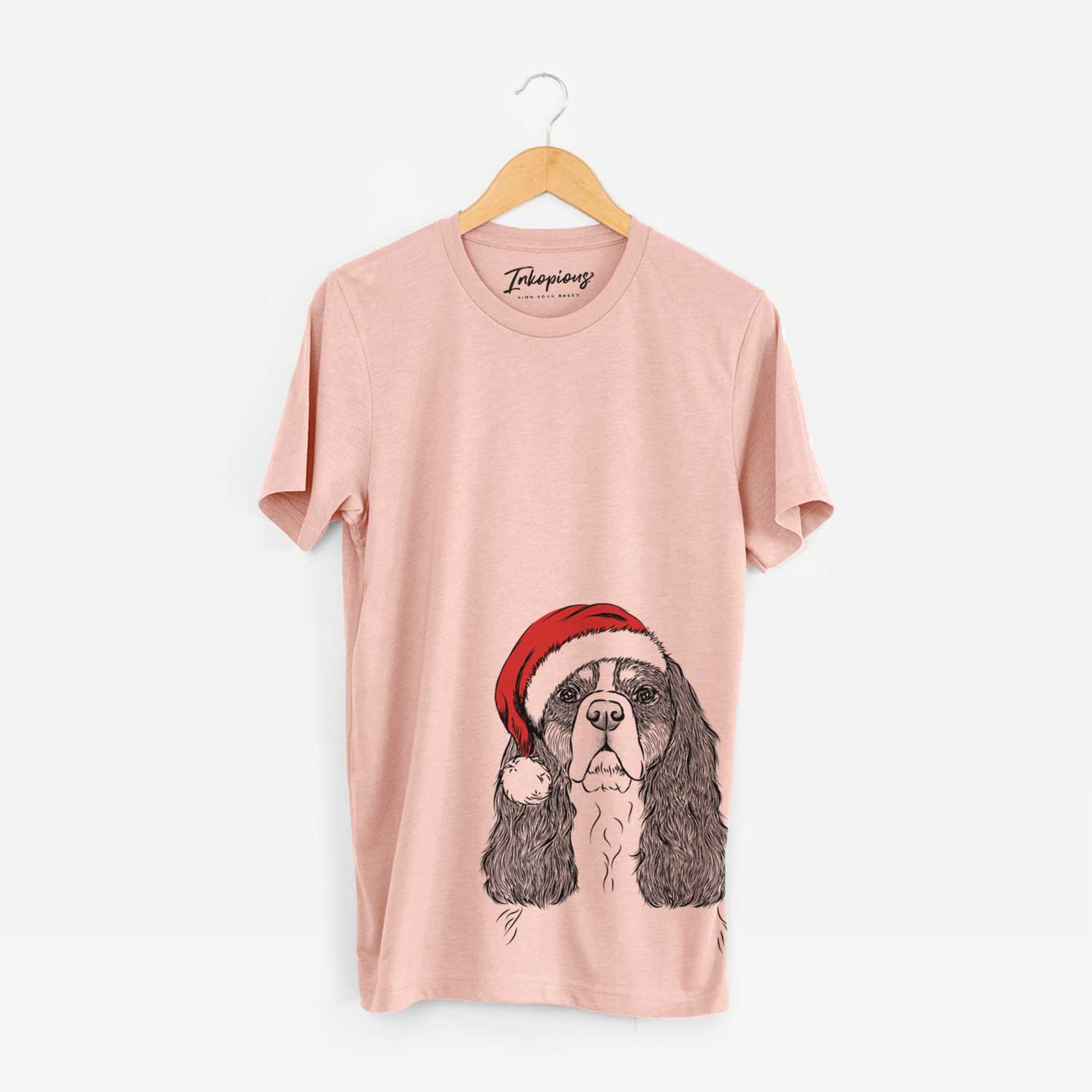 Hand-drawn sketch of Sebastian the Cavalier King Charles Spaniel wearing a Santa hat on a Peach Unisex crewneck
