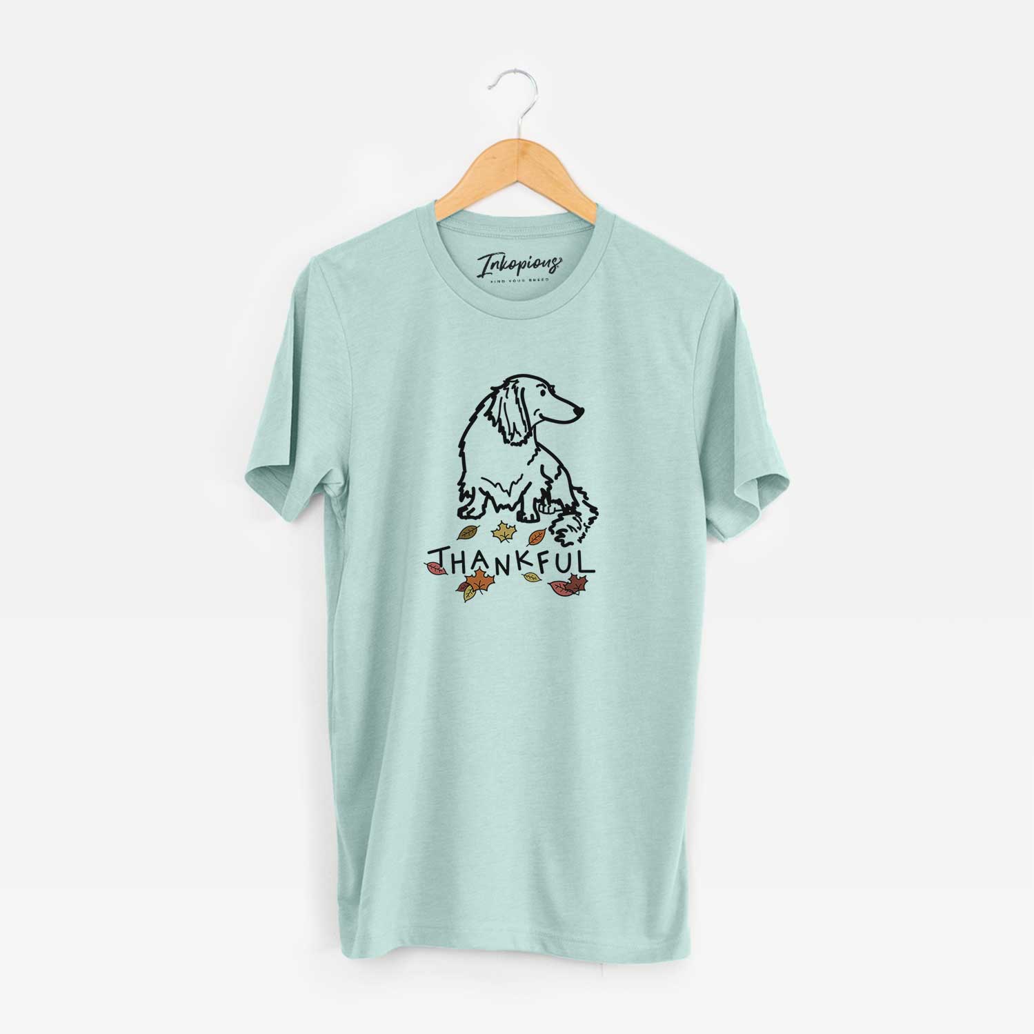 Minimalist line drawing of Bella the Dachshund with 'Thankful' lettering on a Heather Sage Unisex crewneck