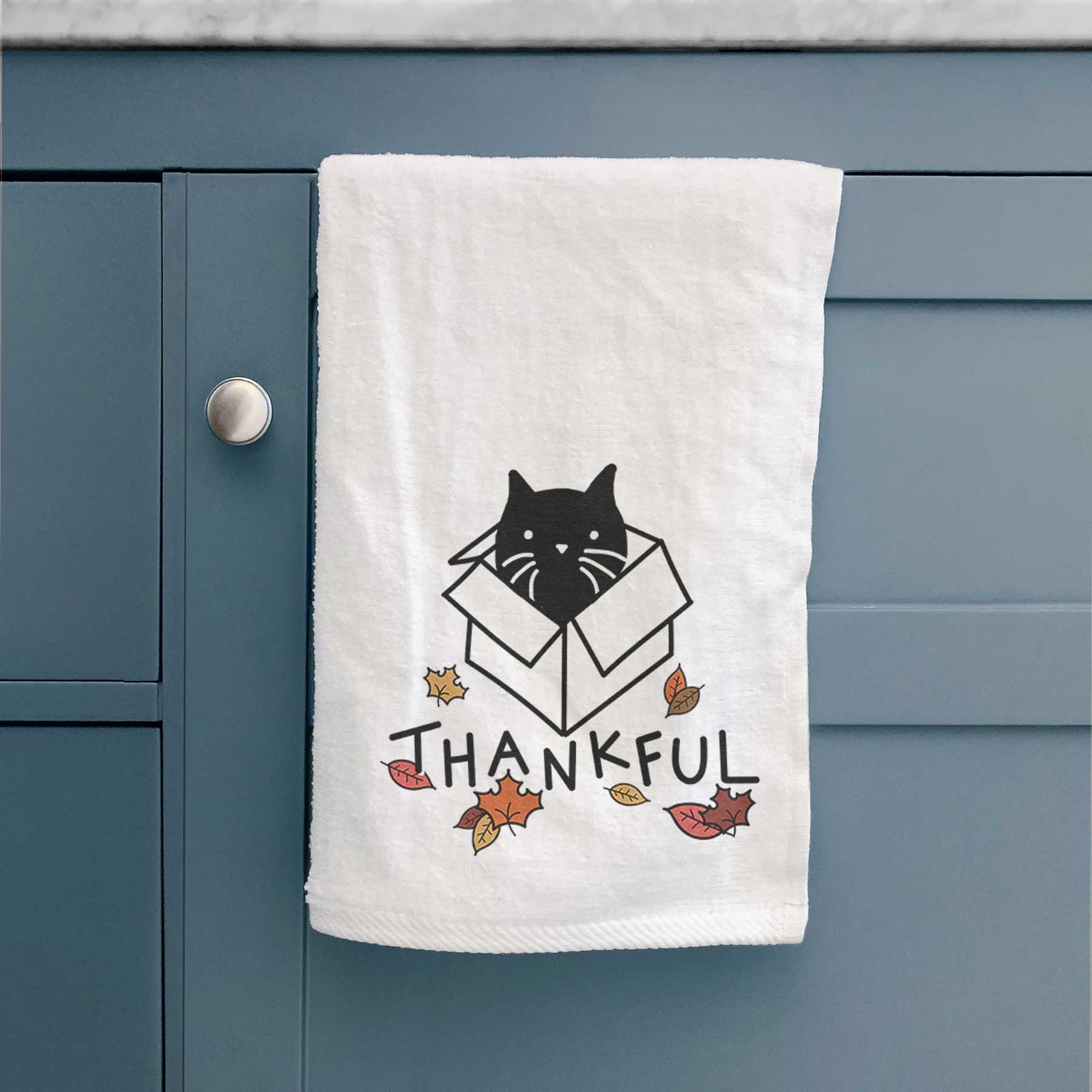 Minimalist line drawing of Doc the Black Cat in a Box with 'Thankful' lettering on a decorative hand towel