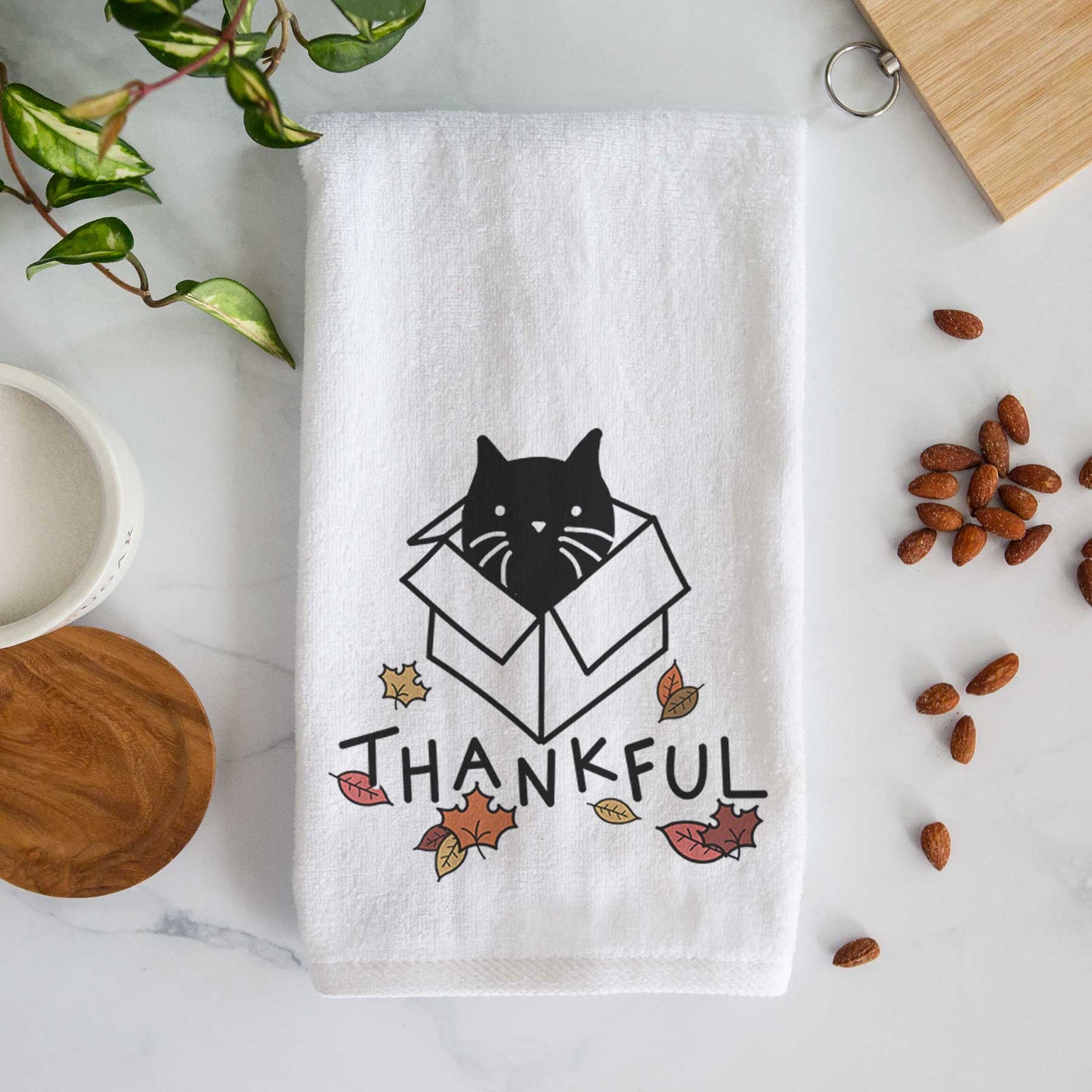 Minimalist line drawing of Doc the Black Cat in a Box with 'Thankful' lettering on a decorative hand towel