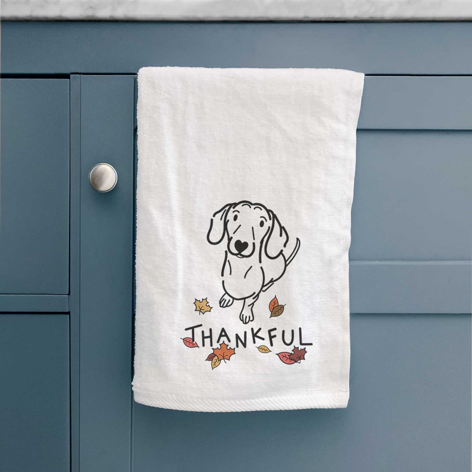 Minimalist line drawing of Moxie the Dachshund with 'Thankful' lettering on a decorative hand towel