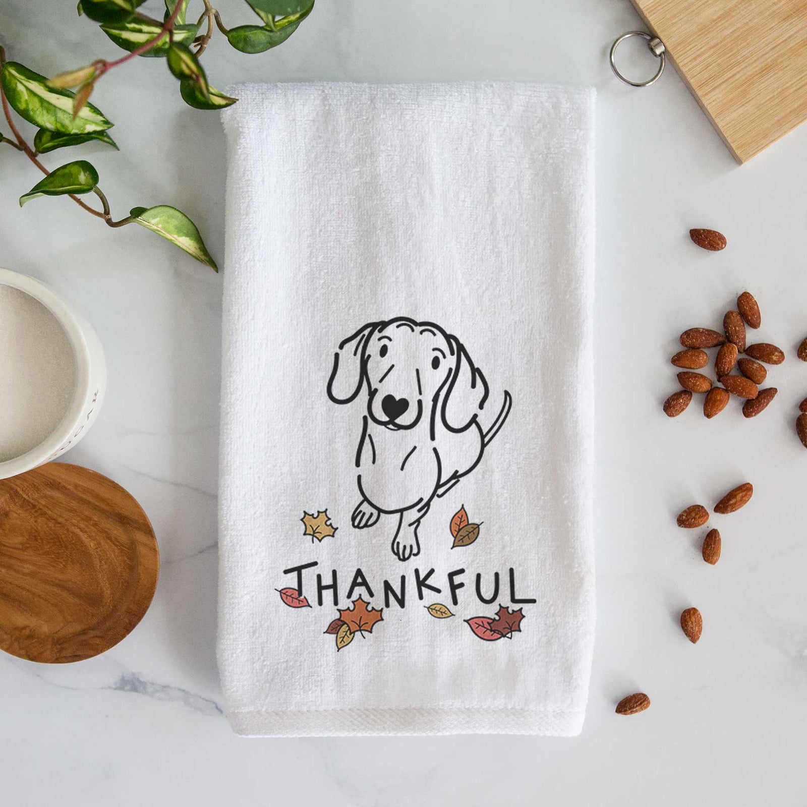 Minimalist line drawing of Moxie the Dachshund with 'Thankful' lettering on a decorative hand towel