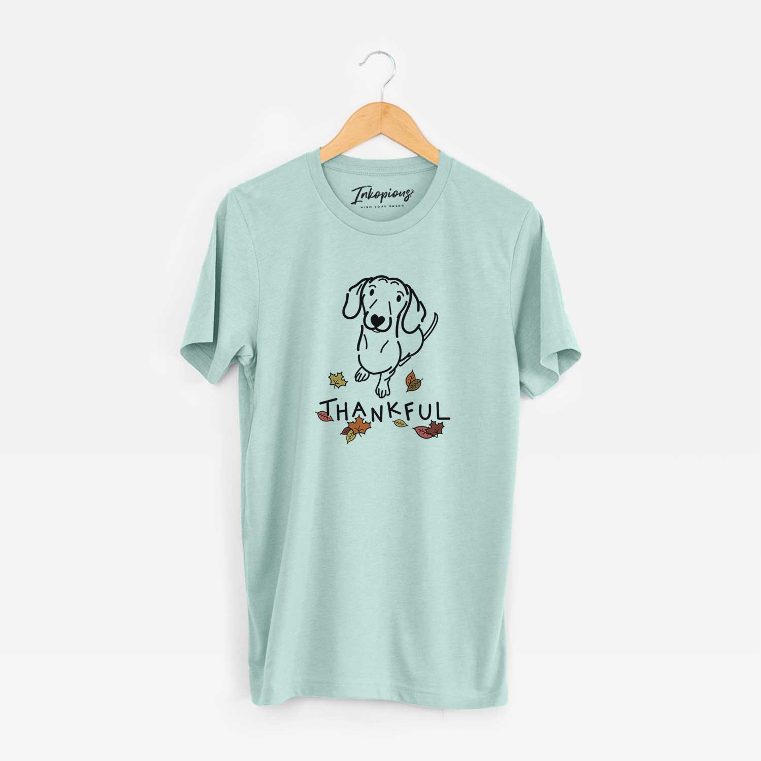 Minimalist line drawing of Moxie the Dachshund with 'Thankful' lettering on a Heather Sage Unisex crewneck