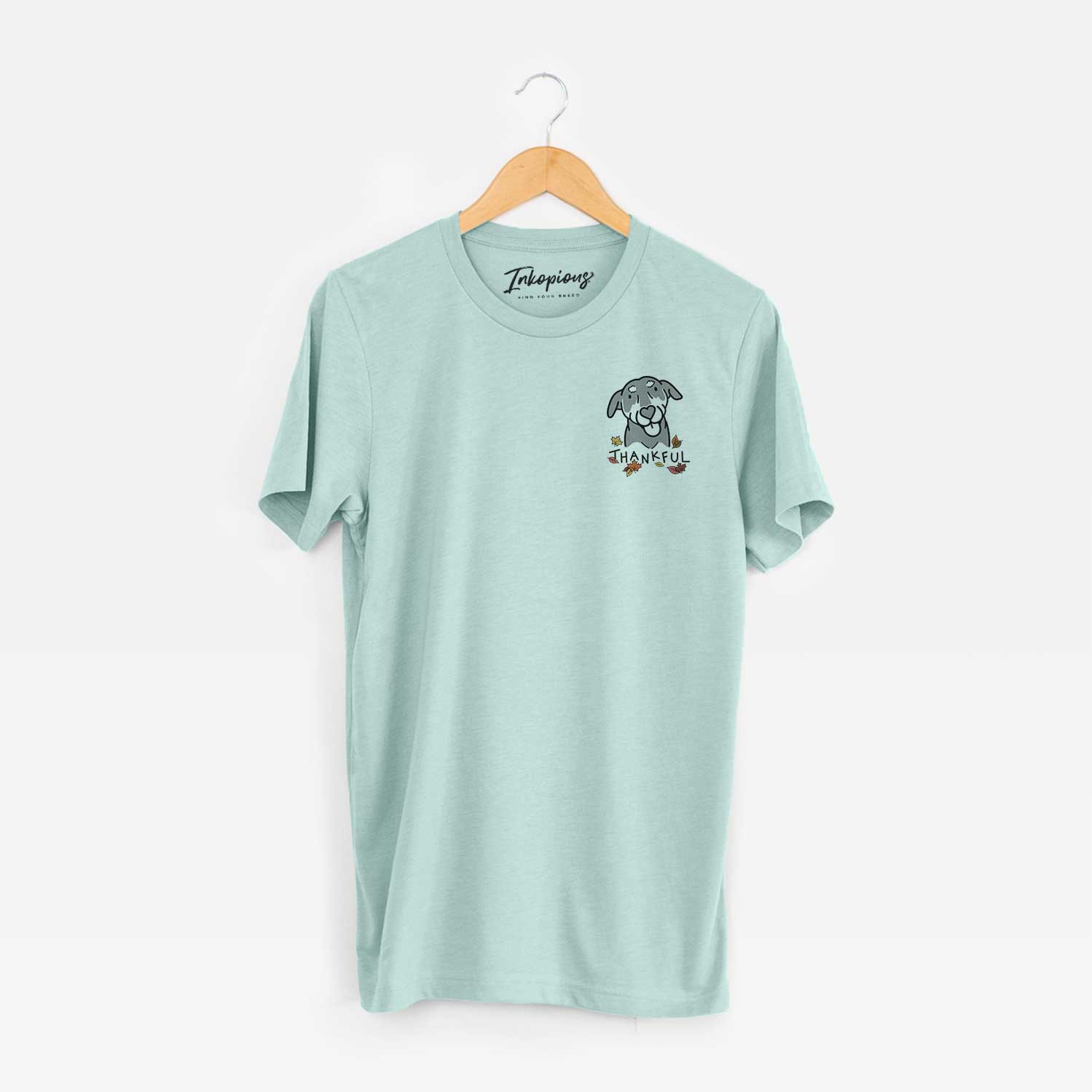 Small chest-pocket minimalist line drawing of Lousia the Mixed Breed with 'Thankful' lettering on a Heather Sage Unisex crewneck