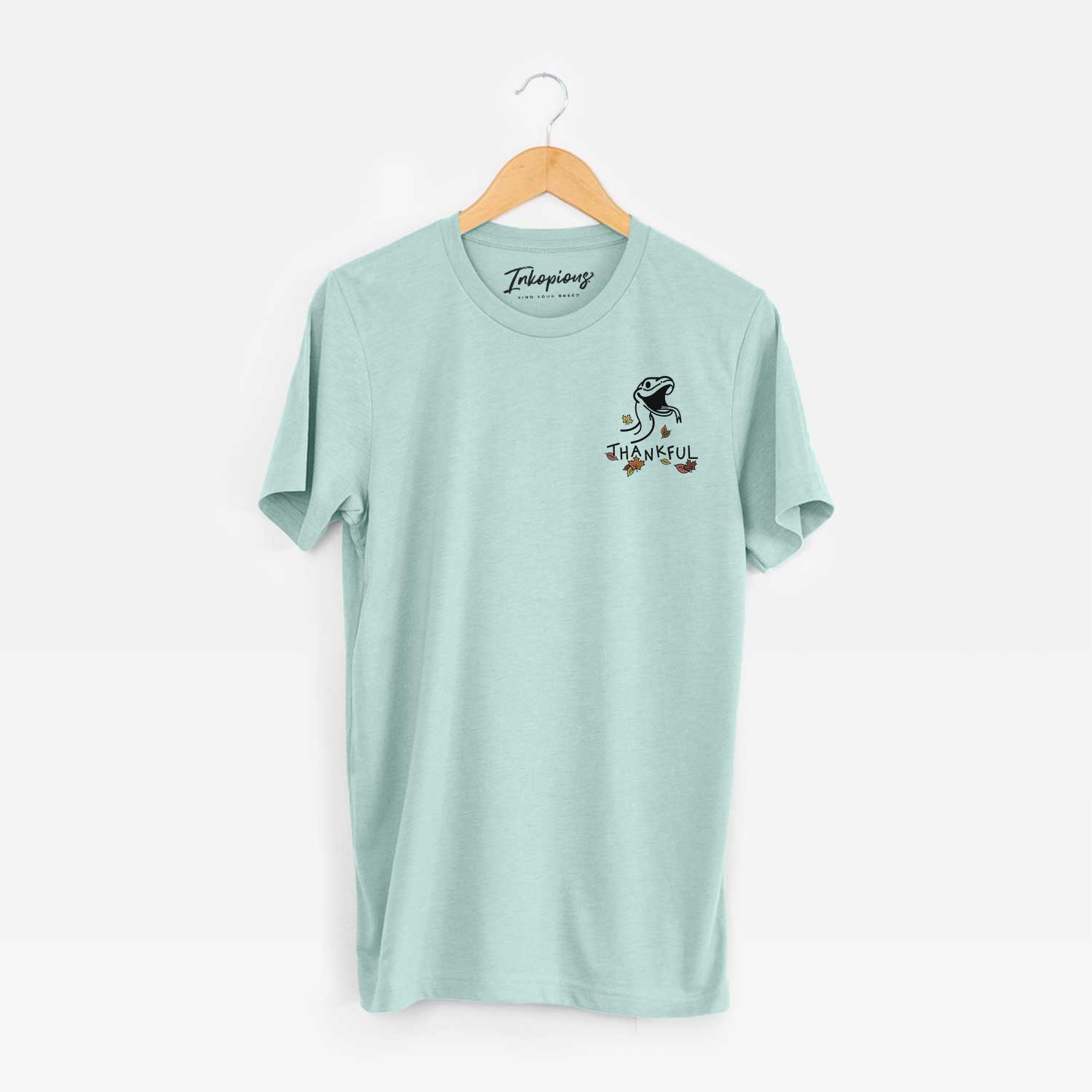 Small chest-pocket minimalist line drawing of Spike the Snake with 'Thankful' lettering on a Heather Sage Unisex crewneck