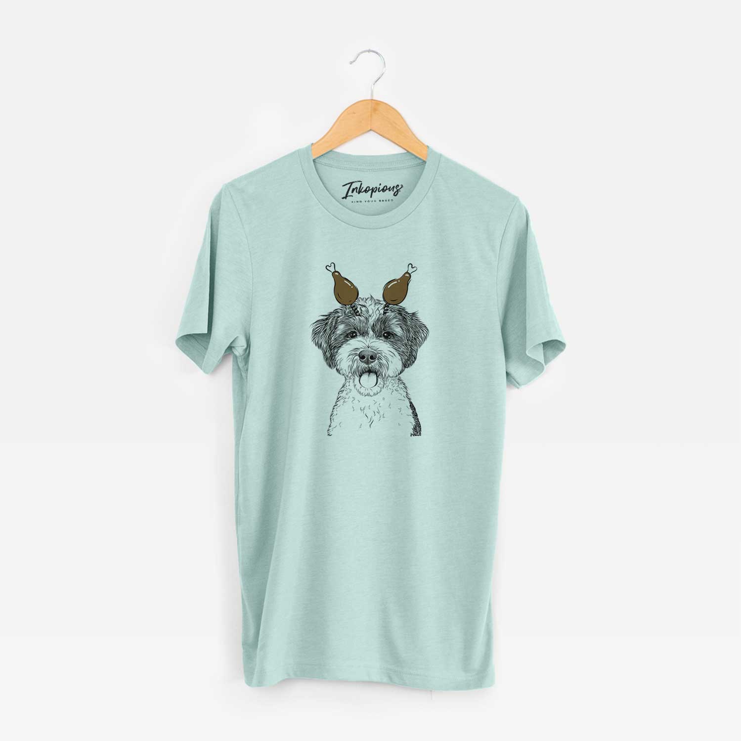 Hand-drawn sketch of Bella the Cockapoo with a Thanksgiving turkey headpiece on a Heather Sage Unisex crewneck