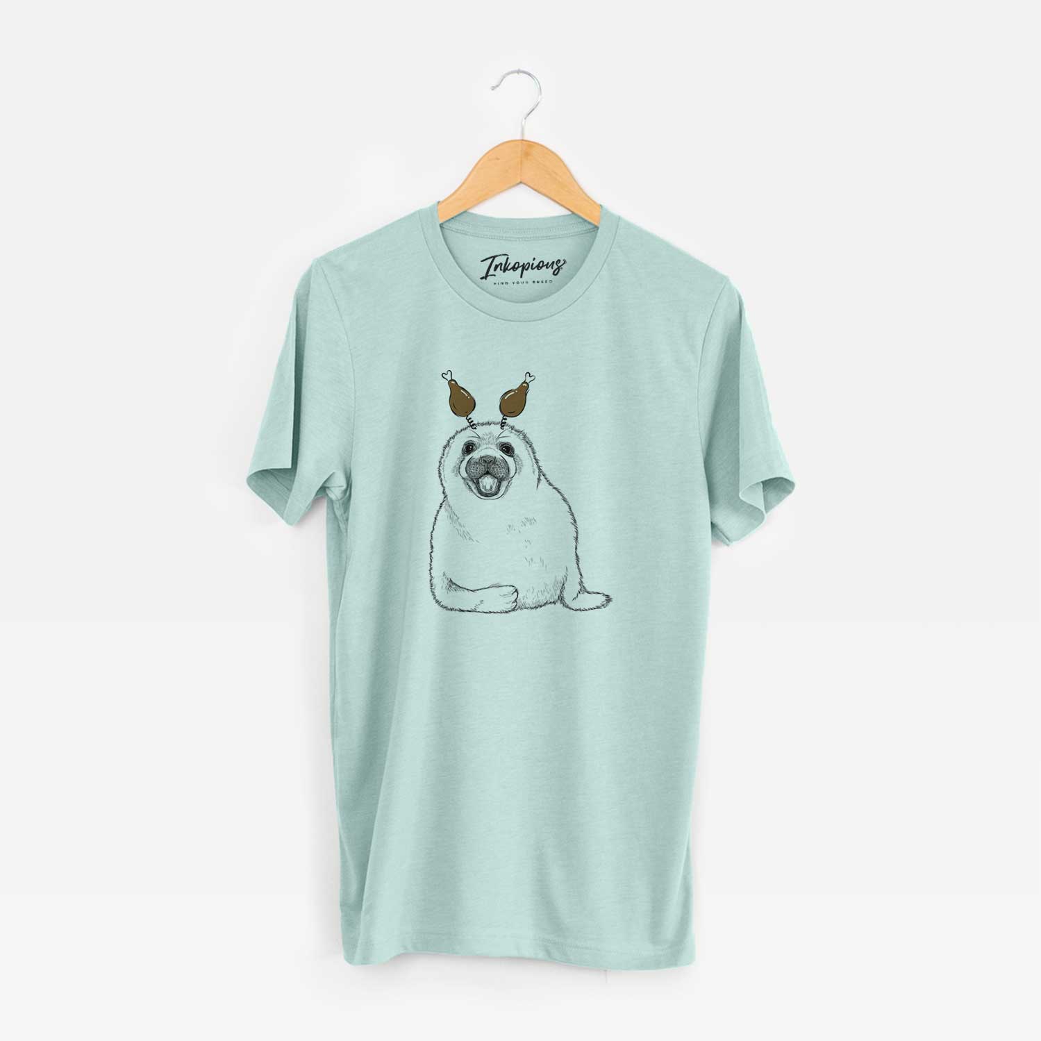 Hand-drawn sketch of Bub the Harp Seal with a Thanksgiving turkey headpiece on a Heather Sage Unisex crewneck