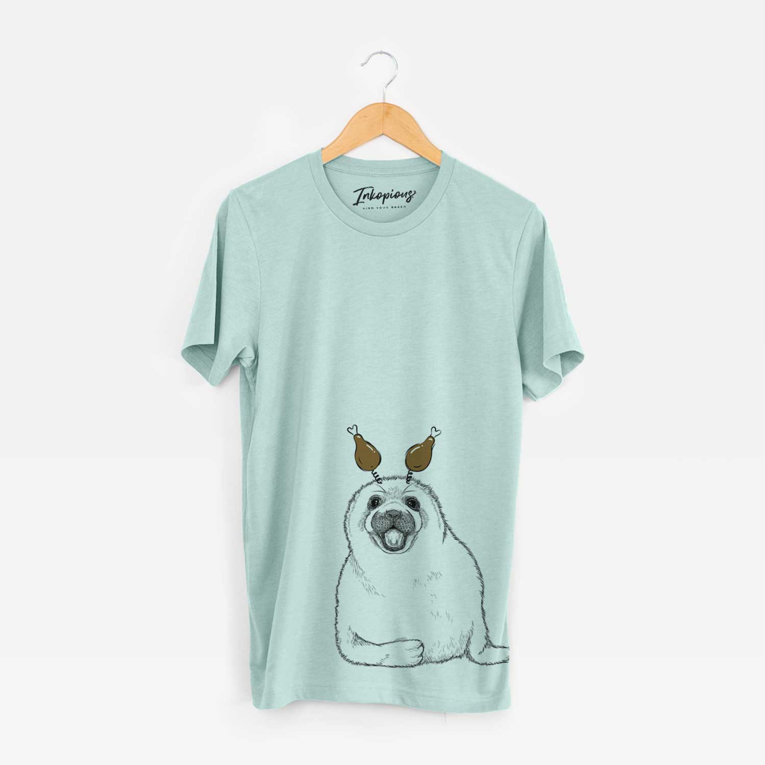 Hand-drawn sketch of Bub the Harp Seal with a Thanksgiving turkey headpiece on a Heather Sage Unisex crewneck