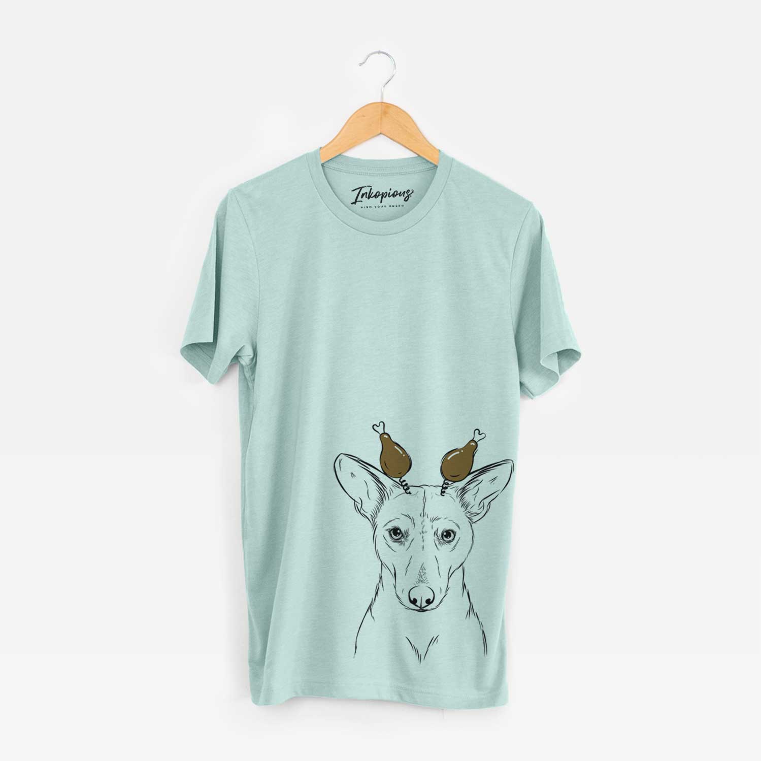 Hand-drawn sketch of Buff the Dorgi with a Thanksgiving turkey headpiece on a Heather Sage Unisex crewneck