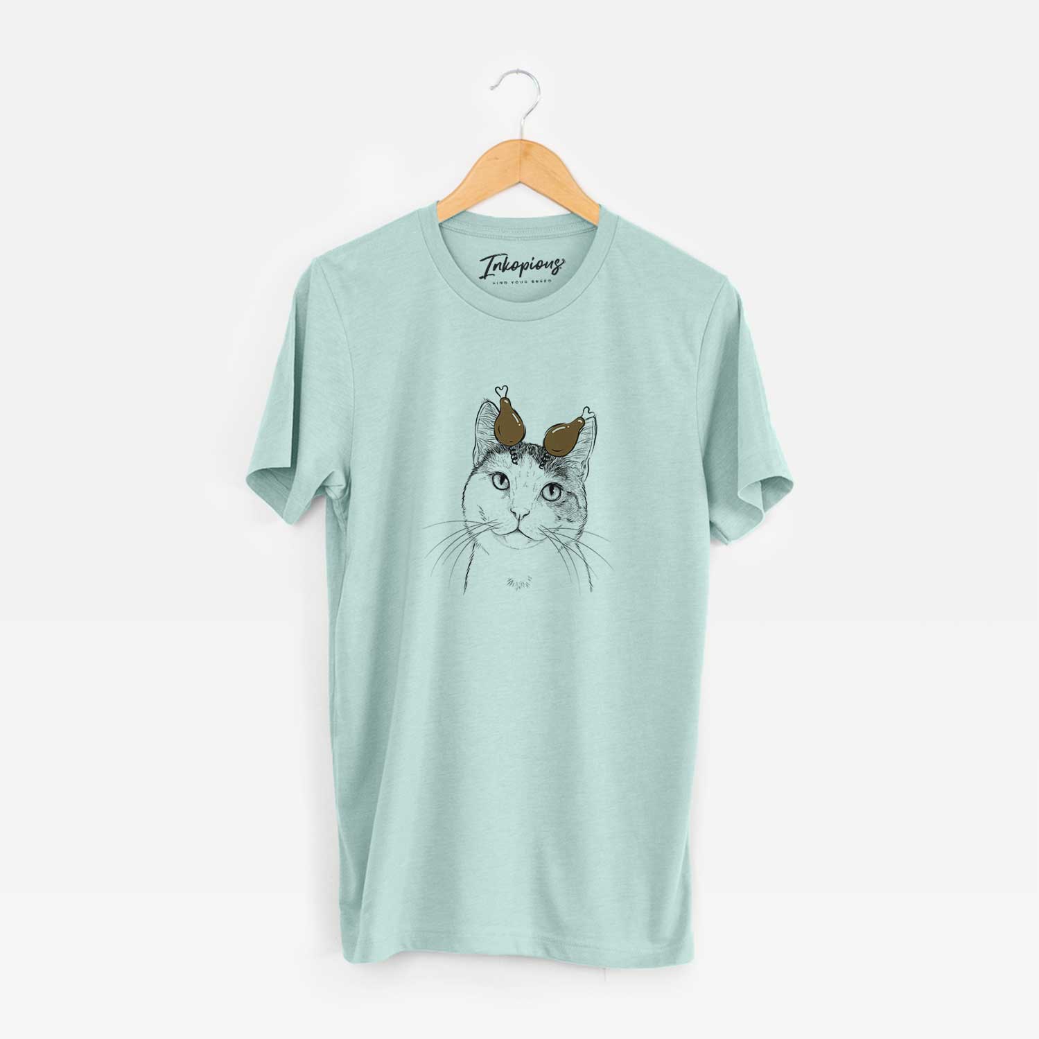 Hand-drawn sketch of Denver the Calico Cat with a Thanksgiving turkey headpiece on a Heather Sage Unisex crewneck