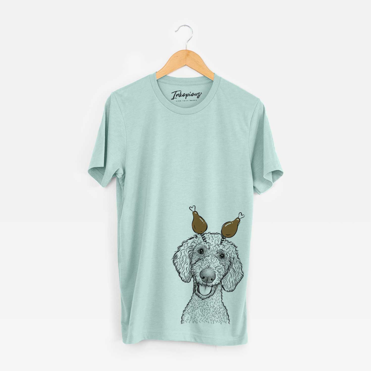 Hand-drawn sketch of Fenway the Goldendoodle with a Thanksgiving turkey headpiece on a Heather Sage Unisex crewneck