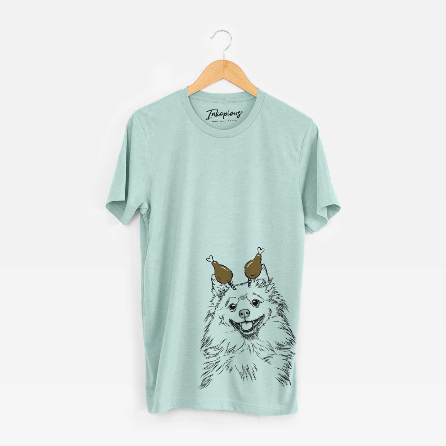 Hand-drawn sketch of Fibi the Spitz with a Thanksgiving turkey headpiece on a Heather Sage Unisex crewneck