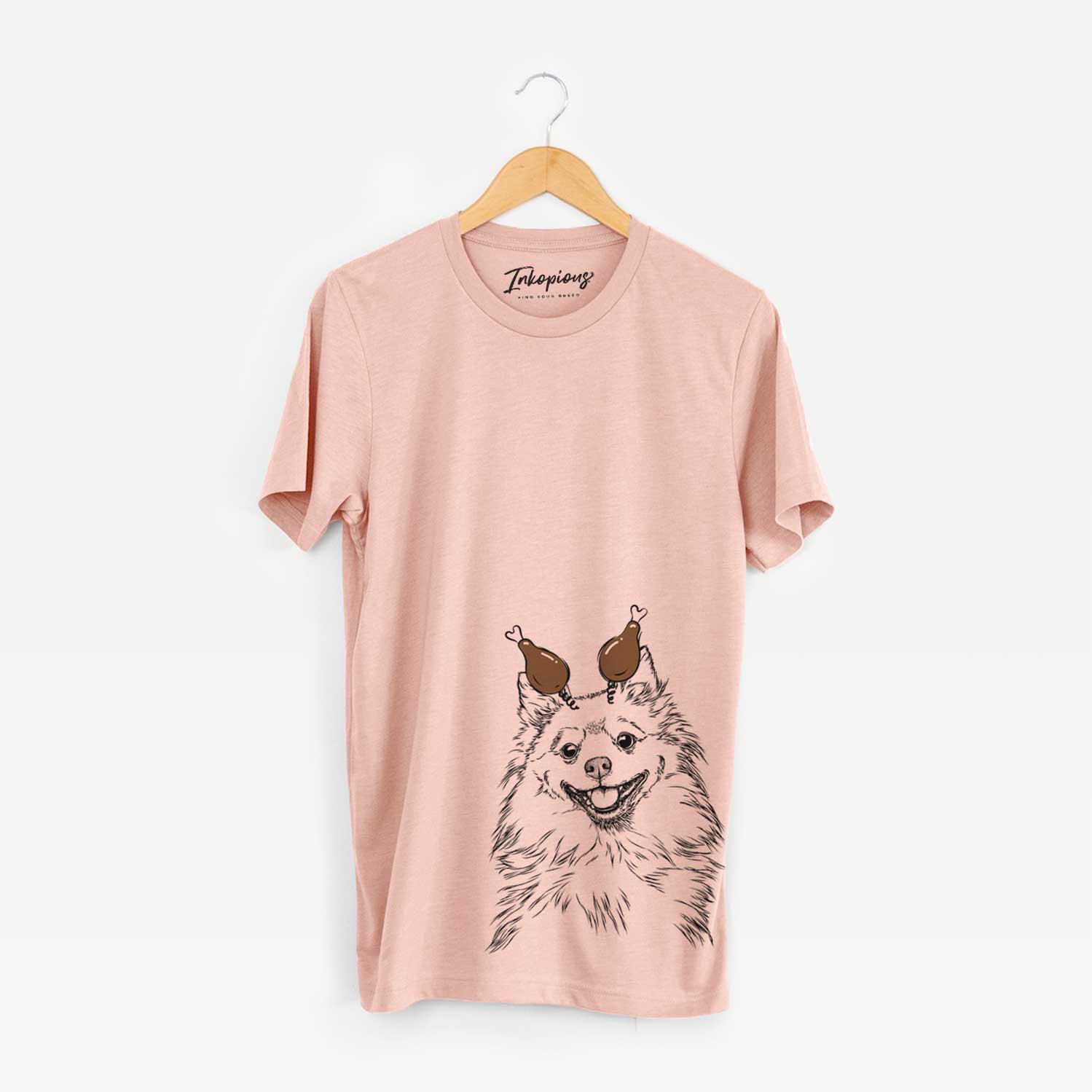 Hand-drawn sketch of Fibi the Spitz with a Thanksgiving turkey headpiece on a Peach Unisex crewneck