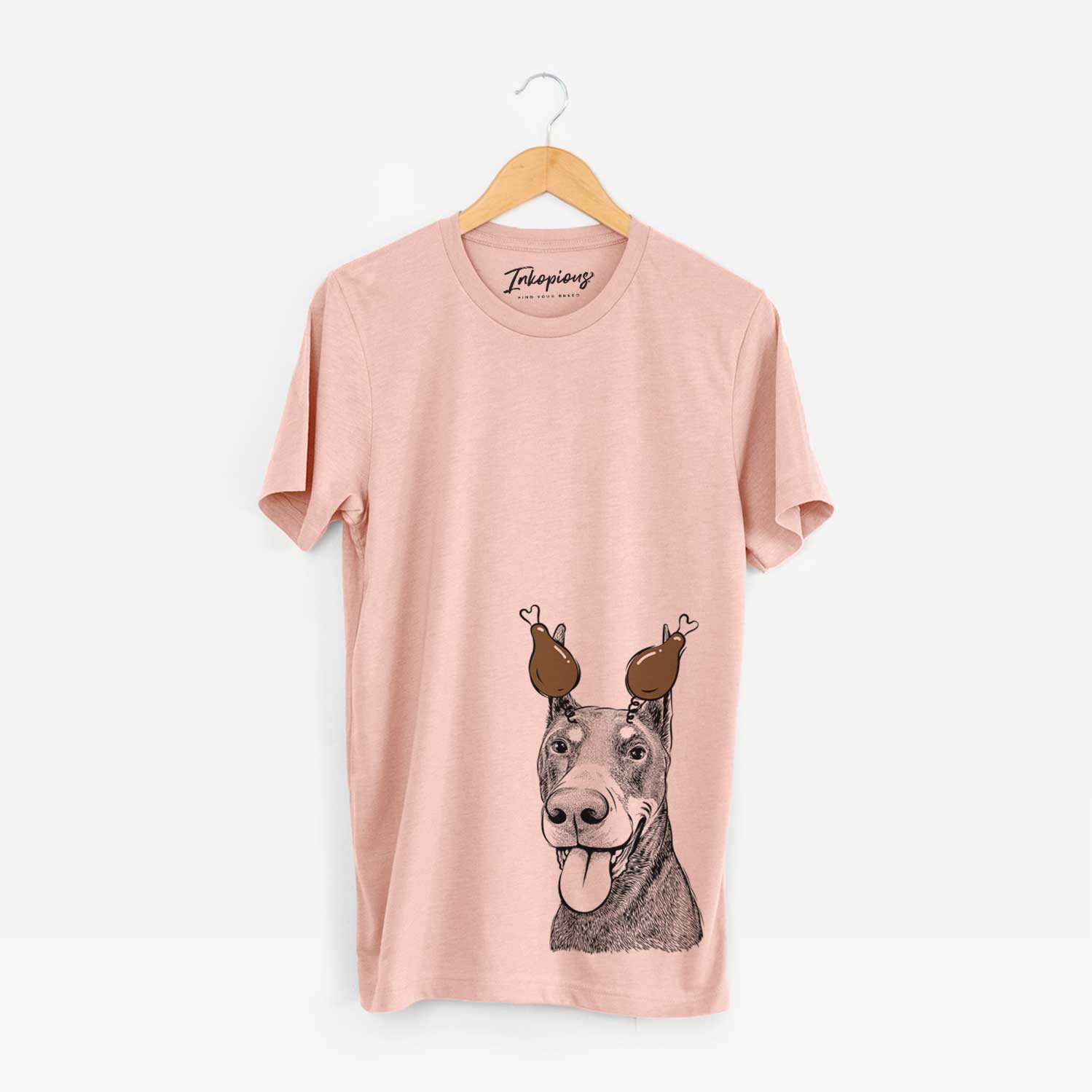 Hand-drawn sketch of Happy Sunny the Doberman Pinscher with a Thanksgiving turkey headpiece on a Peach Unisex crewneck