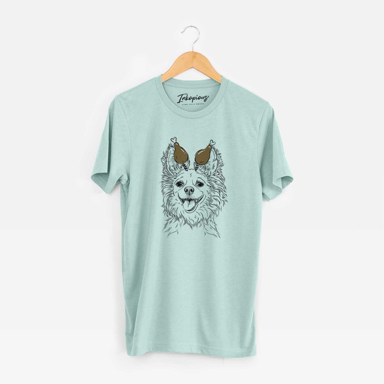 Hand-drawn sketch of Jasper the Pomchi with a Thanksgiving turkey headpiece on a Heather Sage Unisex crewneck