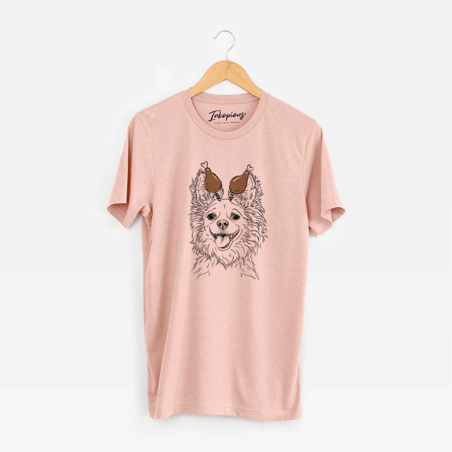 Hand-drawn sketch of Jasper the Pomchi with a Thanksgiving turkey headpiece on a Peach Unisex crewneck