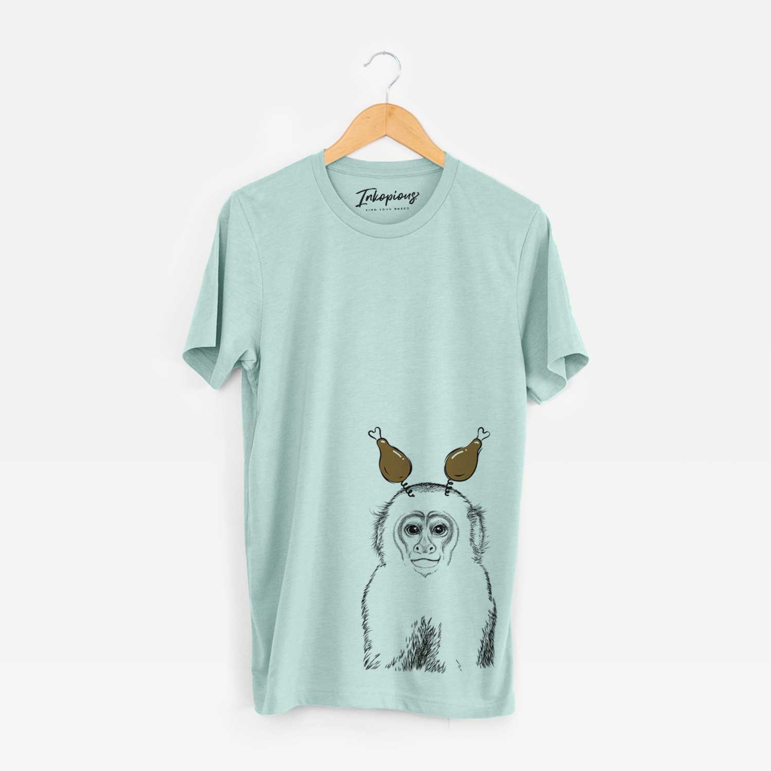 Hand-drawn sketch of Marcel the Capuchin Monkey with a Thanksgiving turkey headpiece on a Heather Sage Unisex crewneck