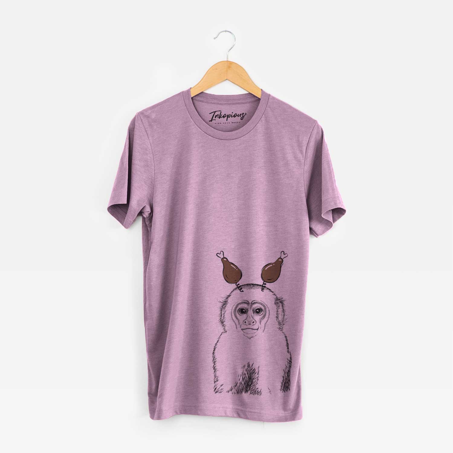 Hand-drawn sketch of Marcel the Capuchin Monkey with a Thanksgiving turkey headpiece on an Orchid Unisex crewneck