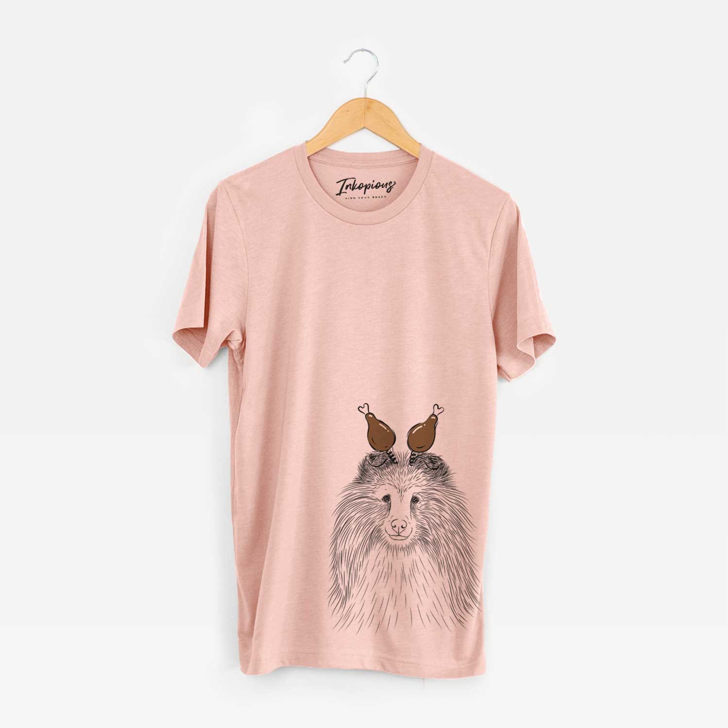 Hand-drawn sketch of Moxie the Shetland Sheepdog with a Thanksgiving turkey headpiece on a Peach Unisex crewneck