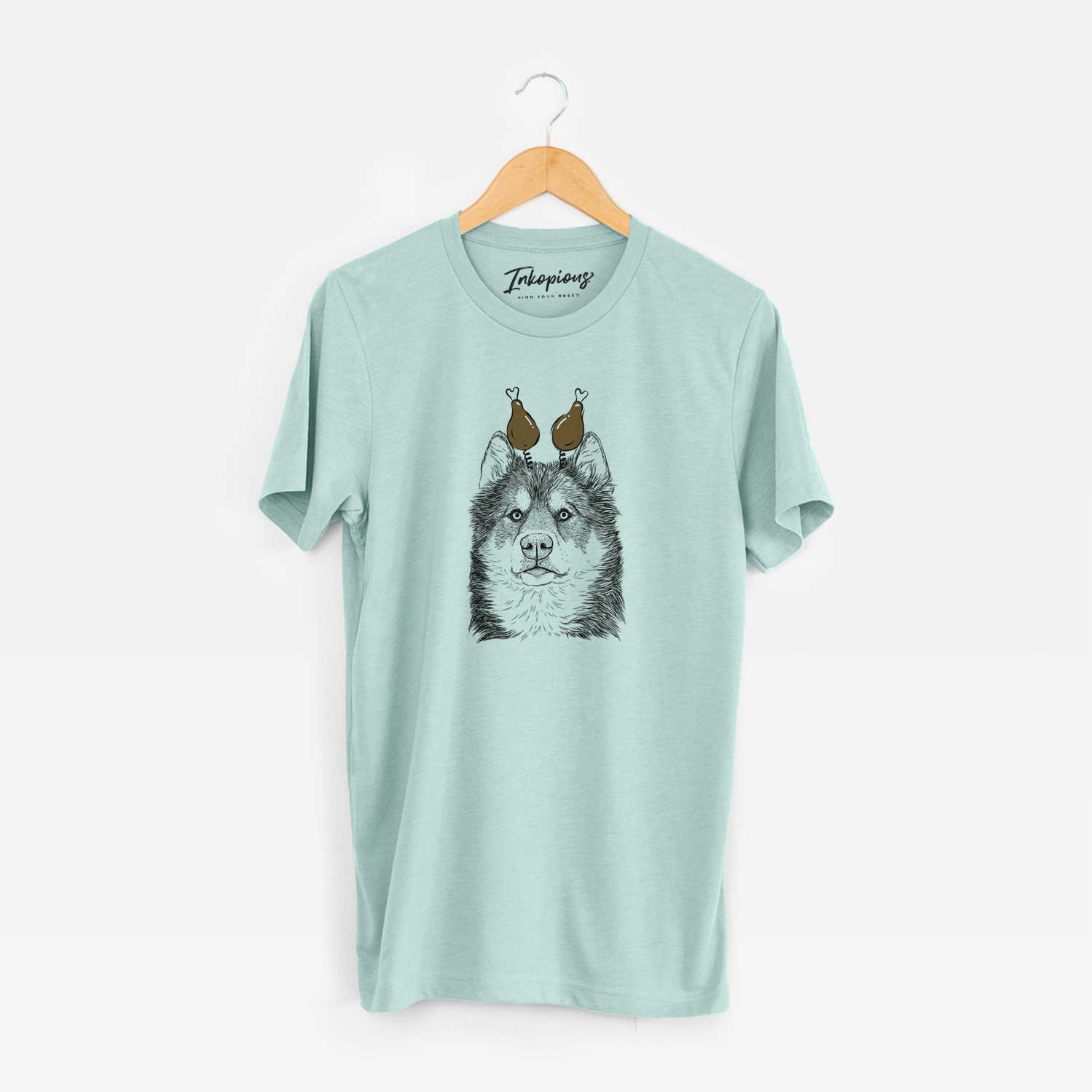 Hand-drawn sketch of Oskar the Canadian Eskimo Dog with a Thanksgiving turkey headpiece on a Heather Sage Unisex crewneck