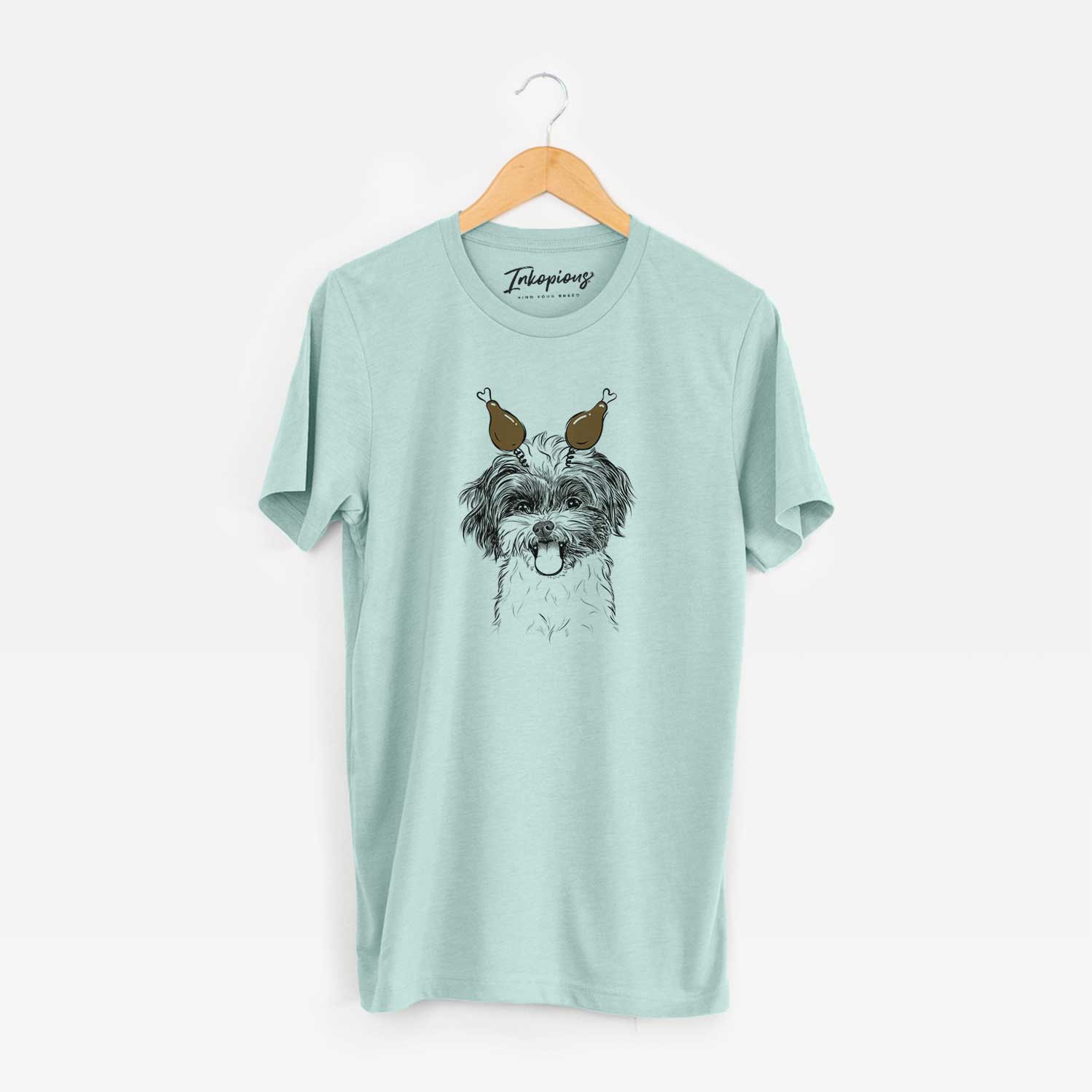 Hand-drawn sketch of Pepper the Shihpoo with a Thanksgiving turkey headpiece on a Heather Sage Unisex crewneck