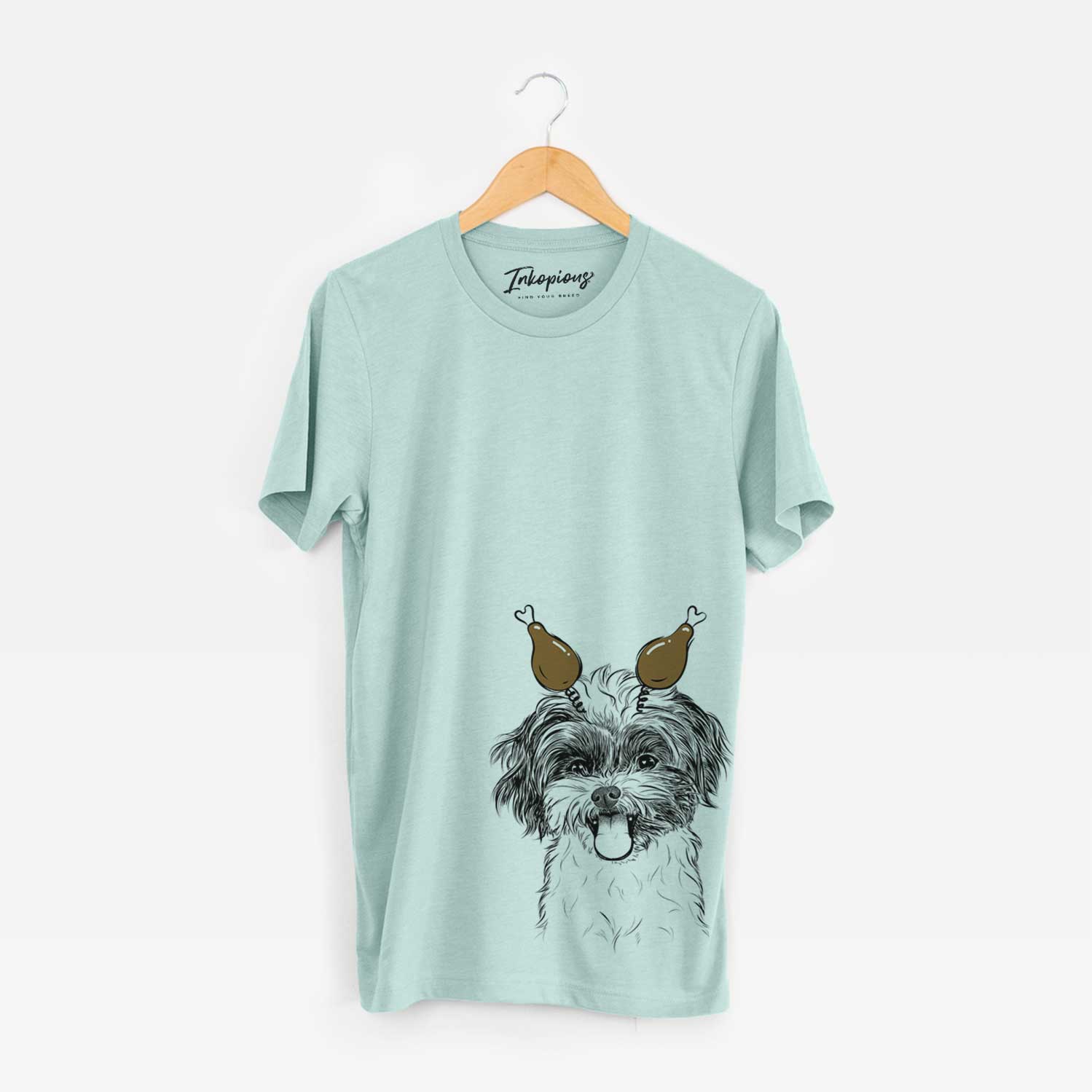 Hand-drawn sketch of Pepper the Shihpoo with a Thanksgiving turkey headpiece on a Heather Sage Unisex crewneck
