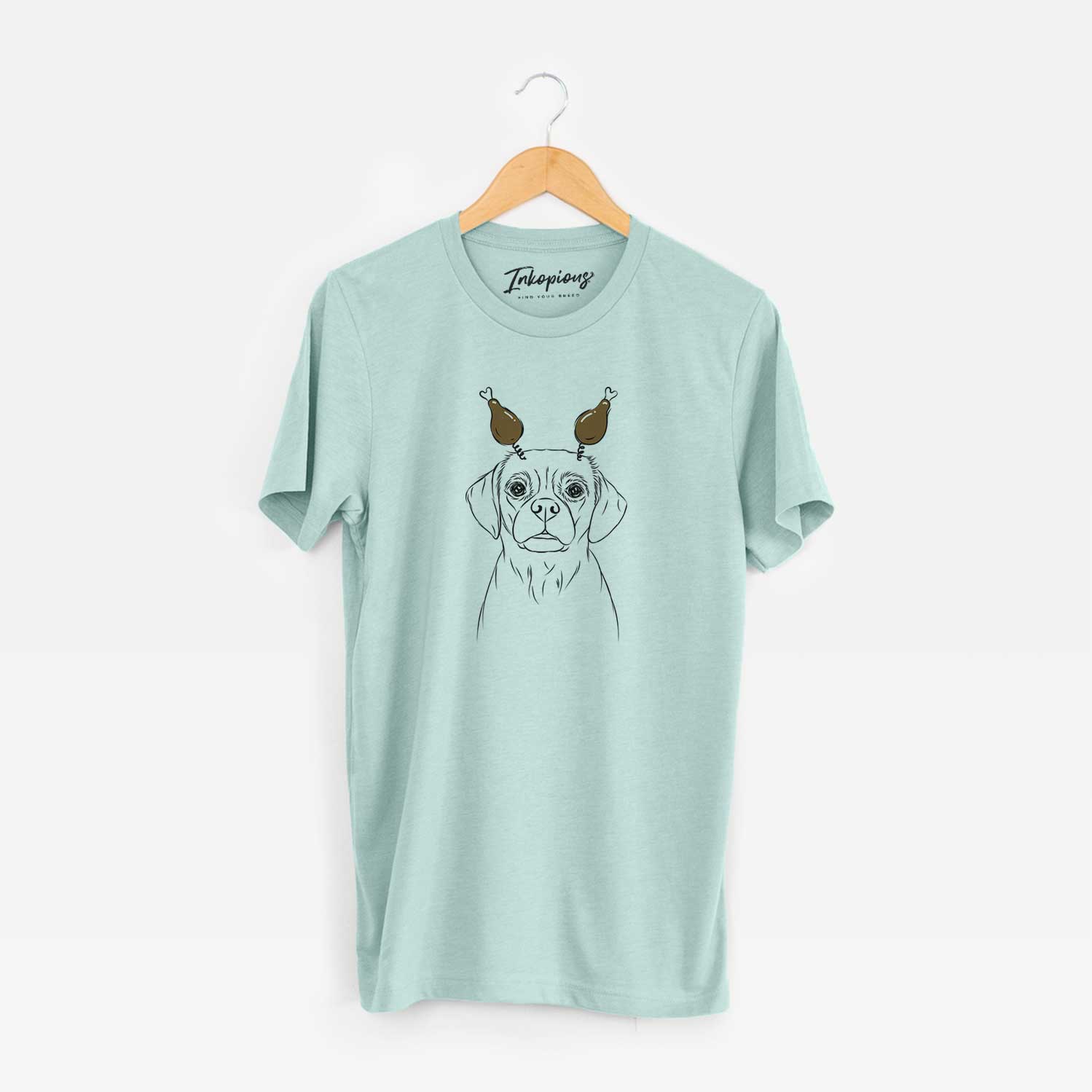 Hand-drawn sketch of Popcorn the Puggle with a Thanksgiving turkey headpiece on a Heather Sage Unisex crewneck