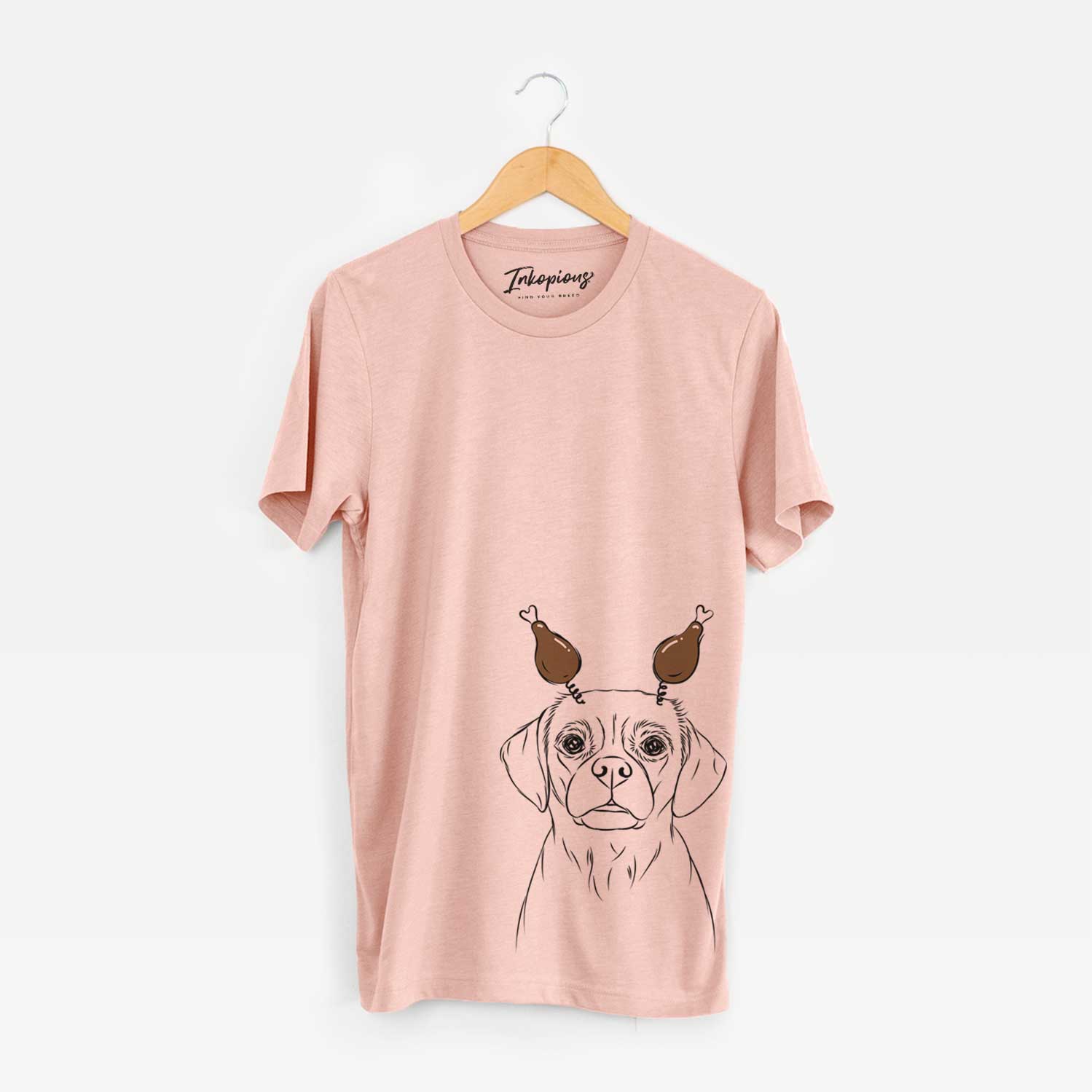 Hand-drawn sketch of Popcorn the Puggle with a Thanksgiving turkey headpiece on a Peach Unisex crewneck