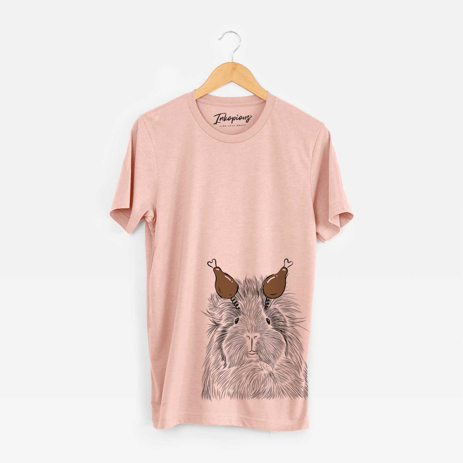 Hand-drawn sketch of Rhino the Guinea Pig with a Thanksgiving turkey headpiece on a Peach Unisex crewneck