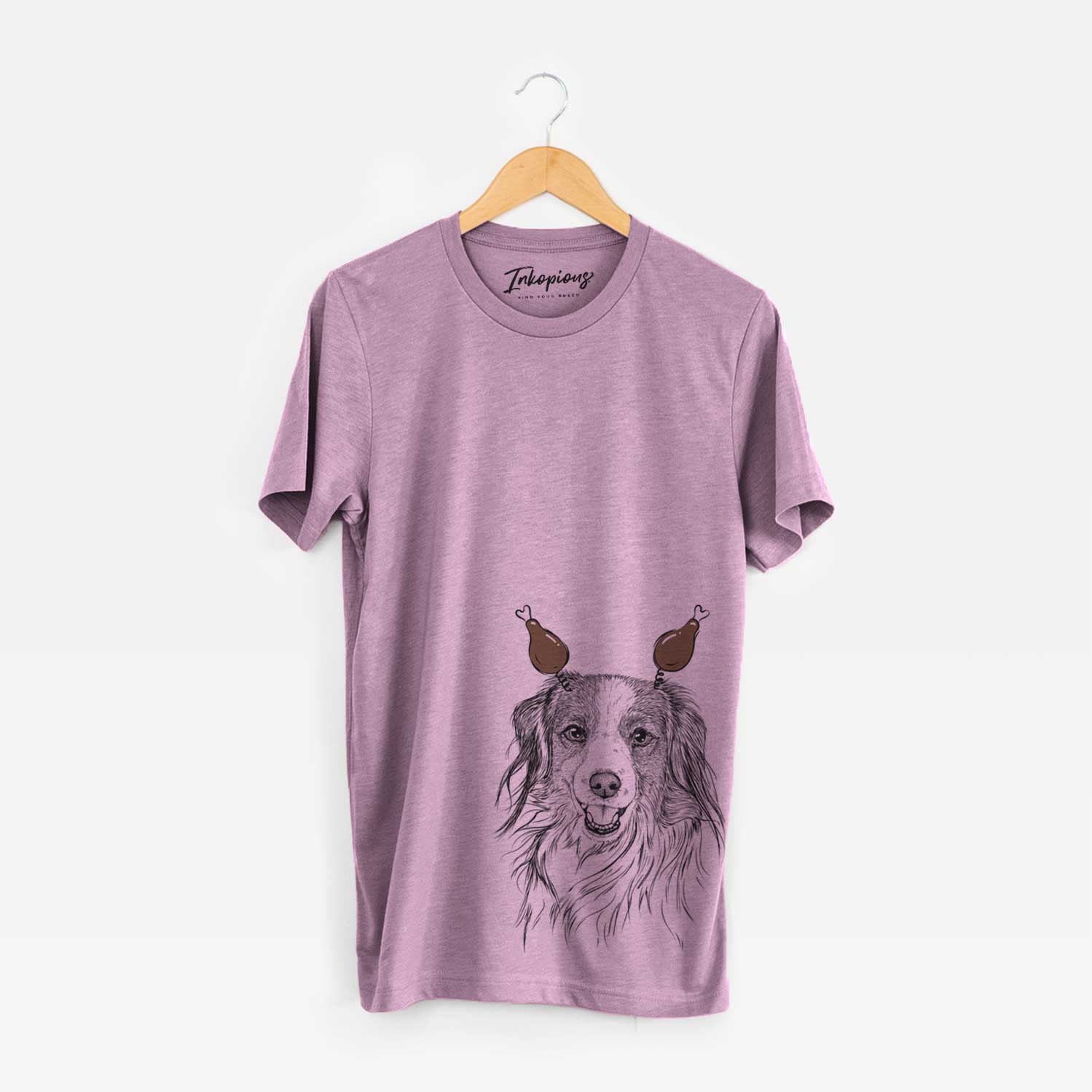 Hand-drawn sketch of Rutger the Nederlandse Kooikerhondje with a Thanksgiving turkey headpiece on an Orchid Unisex crewneck