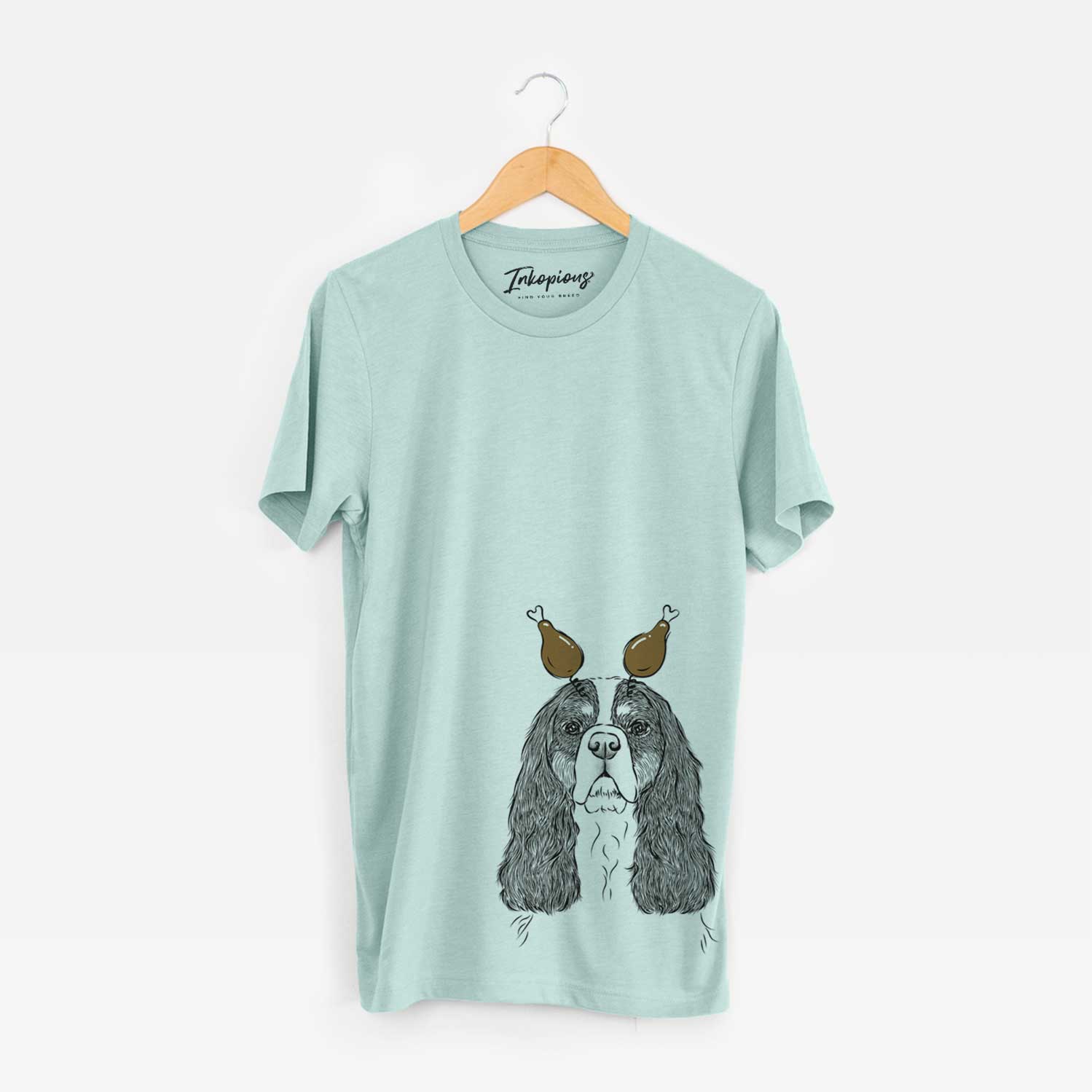 Hand-drawn sketch of Sebastian the Cavalier King Charles Spaniel with a Thanksgiving turkey headpiece on a Heather Sage Unisex crewneck