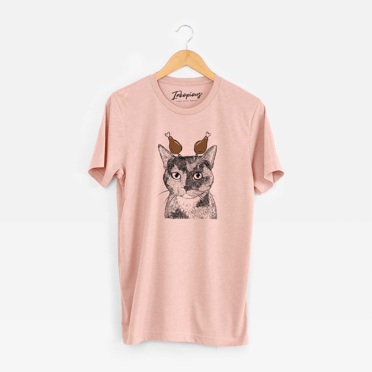 Hand-drawn sketch of Spooky Kitty the Tortoiseshell Cat with a Thanksgiving turkey headpiece on a Peach Unisex crewneck