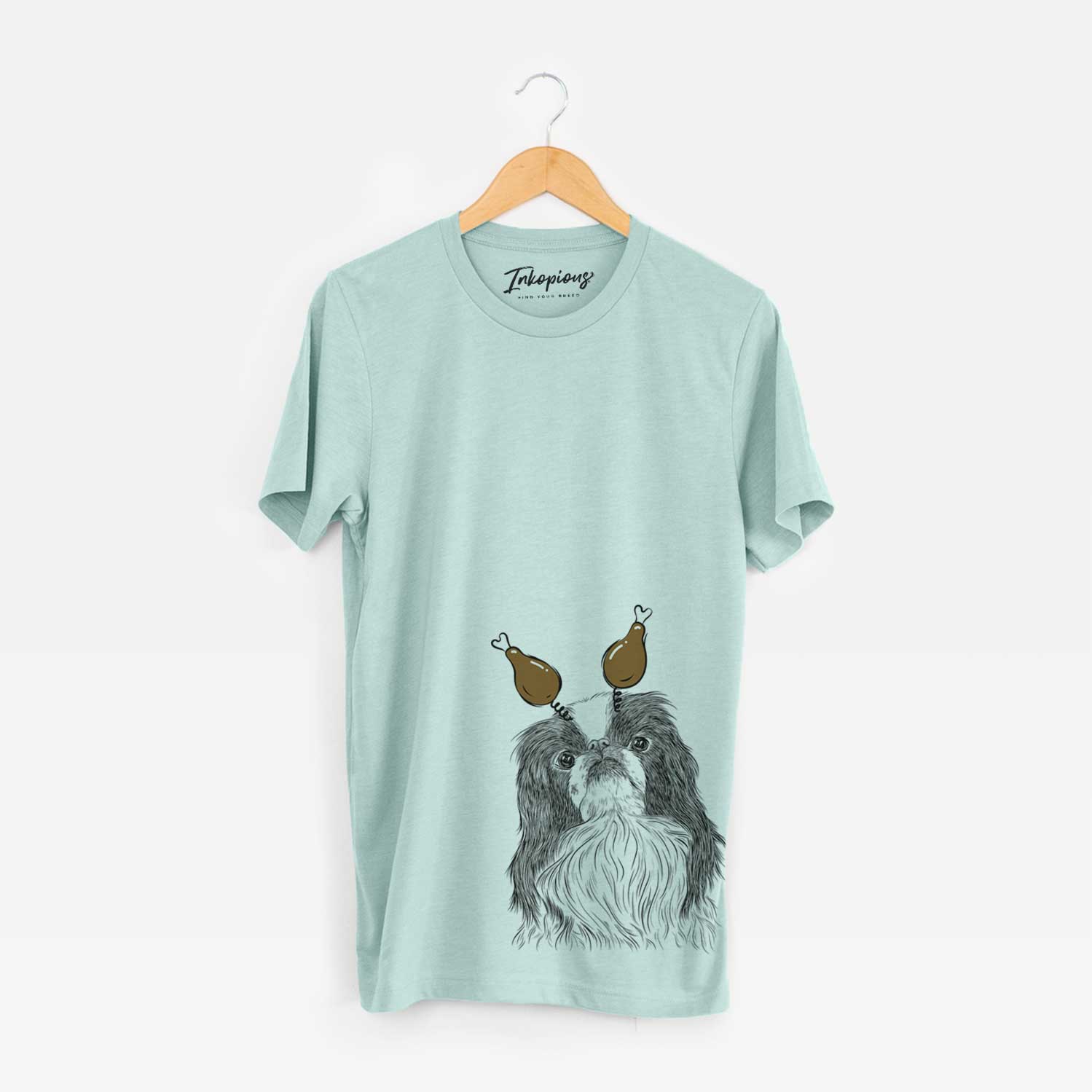 Hand-drawn sketch of Suki the Japanese Chin with a Thanksgiving turkey headpiece on a Heather Sage Unisex crewneck