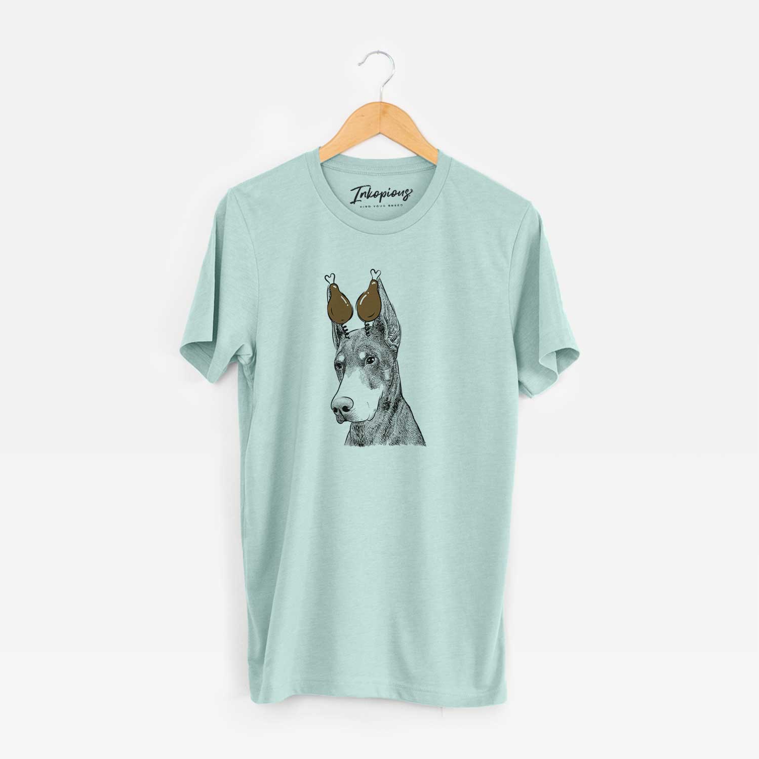 Hand-drawn sketch of Sunny the Doberman Pinscher with a Thanksgiving turkey headpiece on a Heather Sage Unisex crewneck