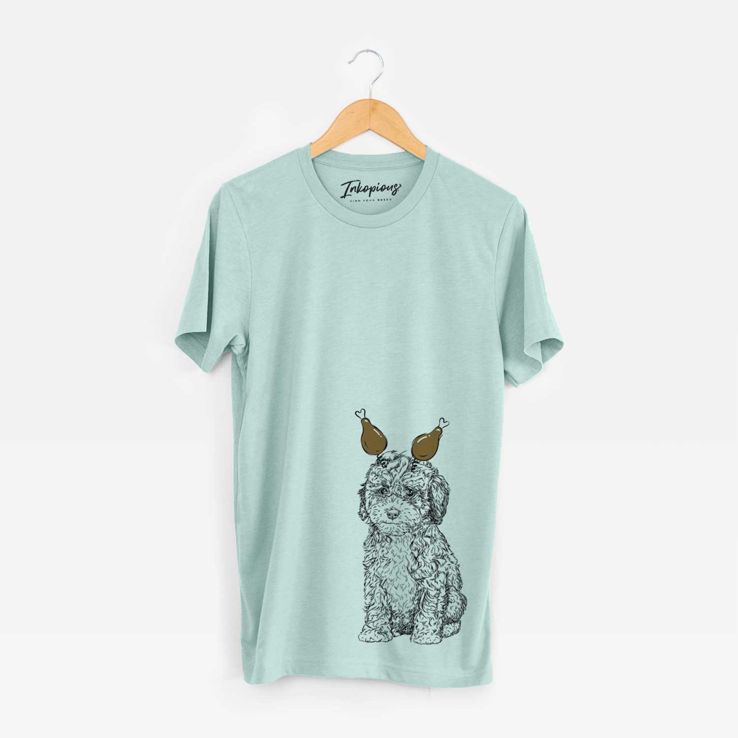 Hand-drawn sketch of Sweet Tea the Mini Doodle with a Thanksgiving turkey headpiece on a Heather Sage Unisex crewneck
