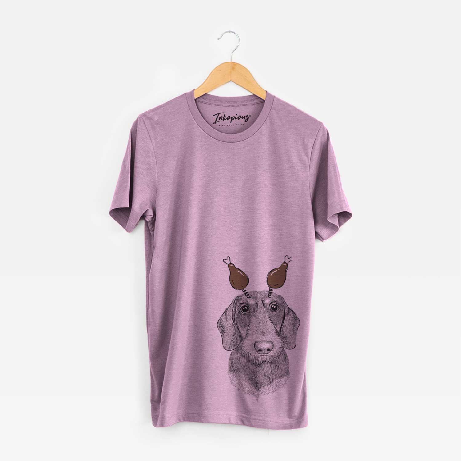 Hand-drawn sketch of Truman the Wirehaired Dachshund with a Thanksgiving turkey headpiece on an Orchid Unisex crewneck
