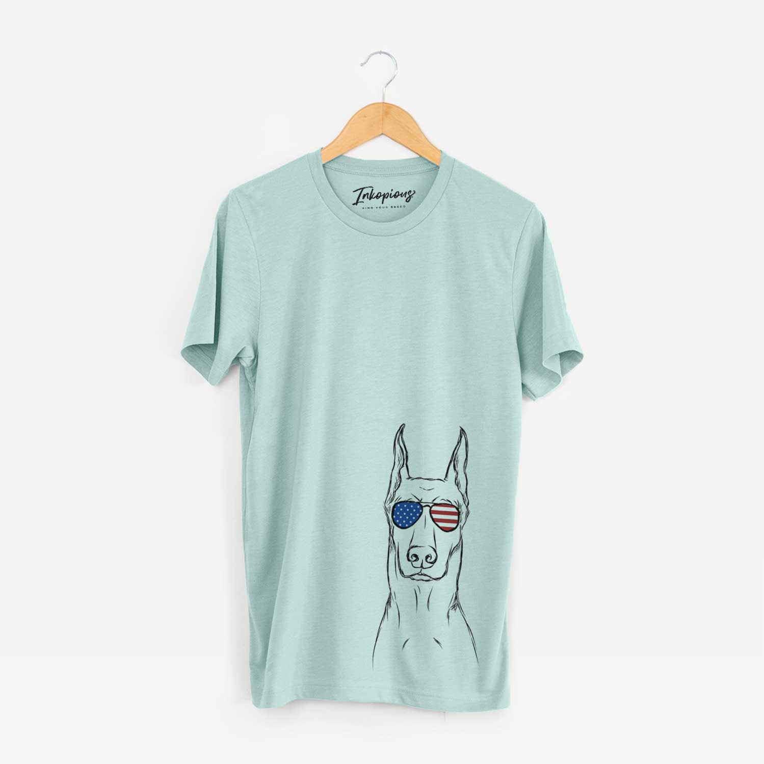 Hand-drawn sketch of Ace the Doberman Pinscher wearing American flag sunglasses on a Heather Sage Unisex crewneck